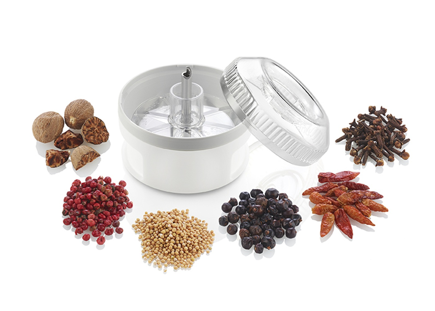 Ein Gewürzzerkleinerer mit Muskatnüssen, rosa Pfeffer, Senfkörnern, Wacholderbeeren, Chilis und Nelken.