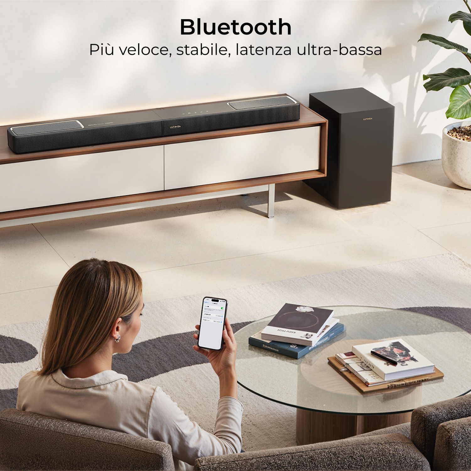 Una donna tiene uno smartphone accanto a un sistema audio con subwoofer.