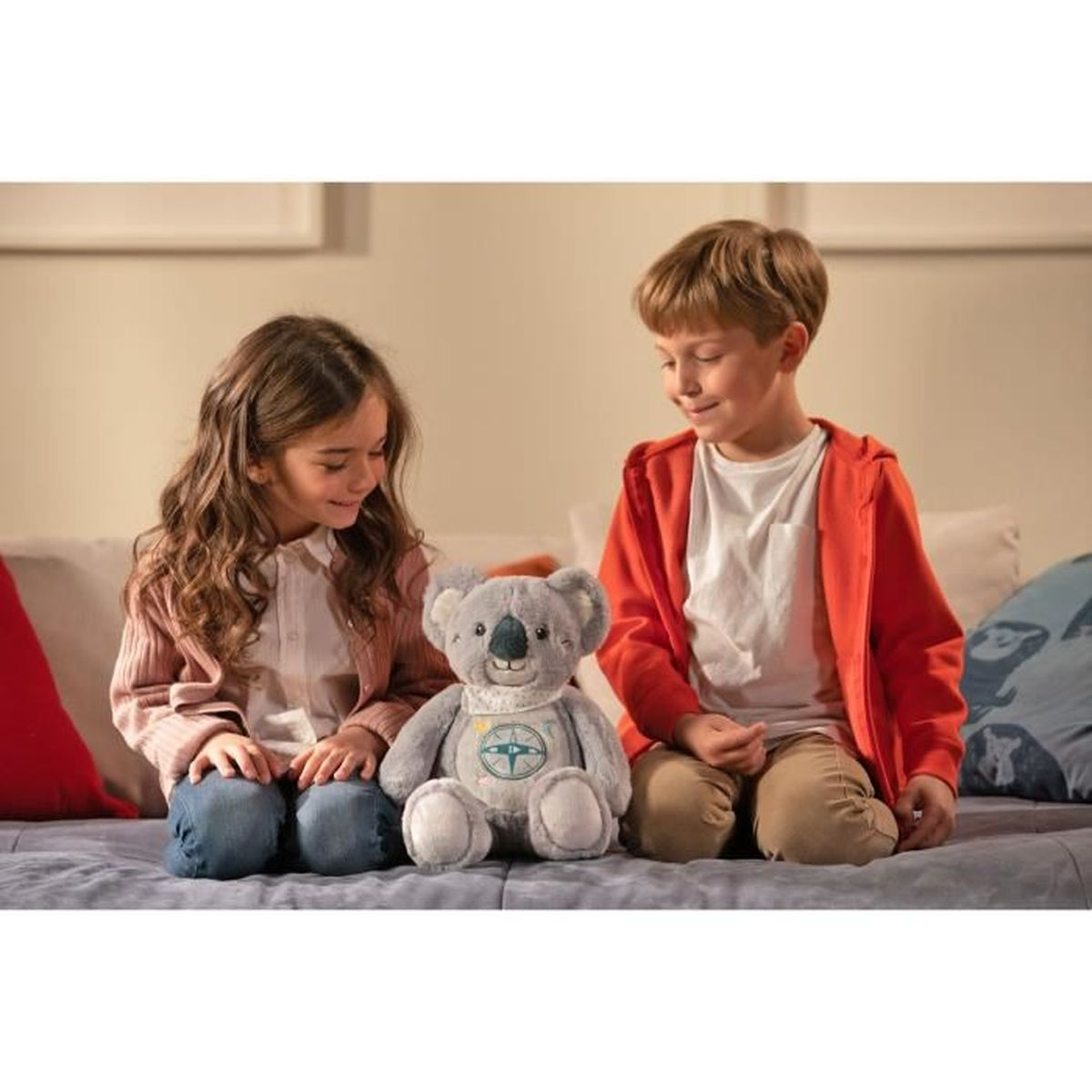 Ein Mädchen und ein Junge sitzen auf einem Bett und betrachten einen Plüschkoalabären.