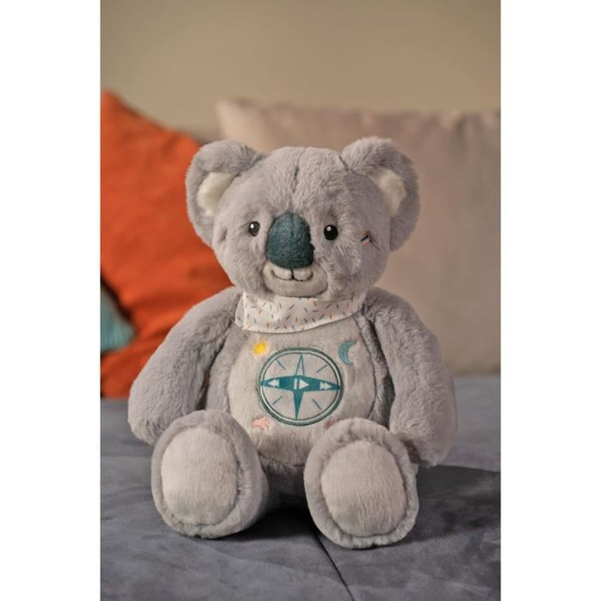 Ein grauer Koala-Plüschtier sitzt, trägt ein Halstuch mit Kompass-Motiv.