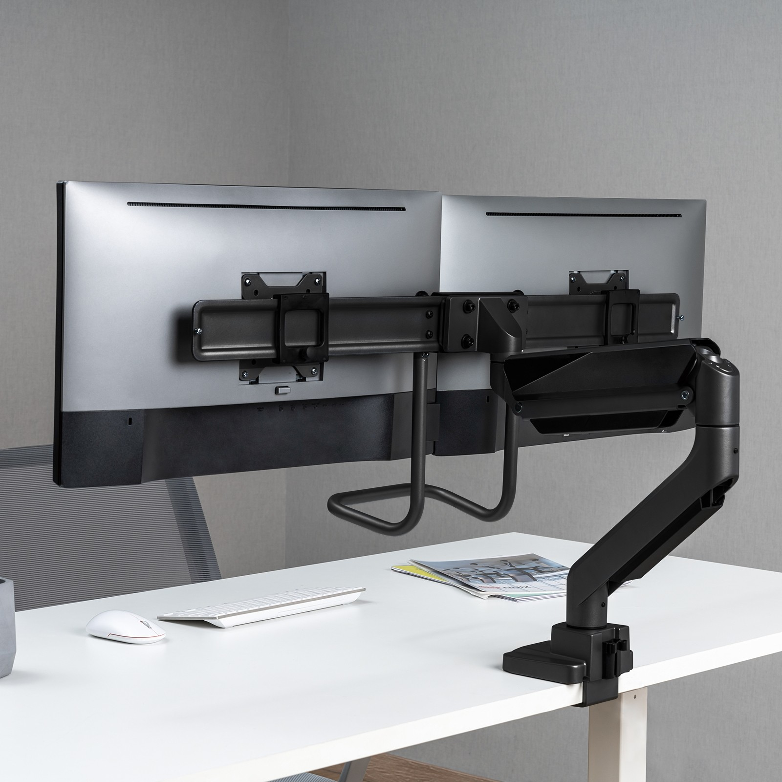 Dos monitores en un escritorio, sujetos por un brazo negro.