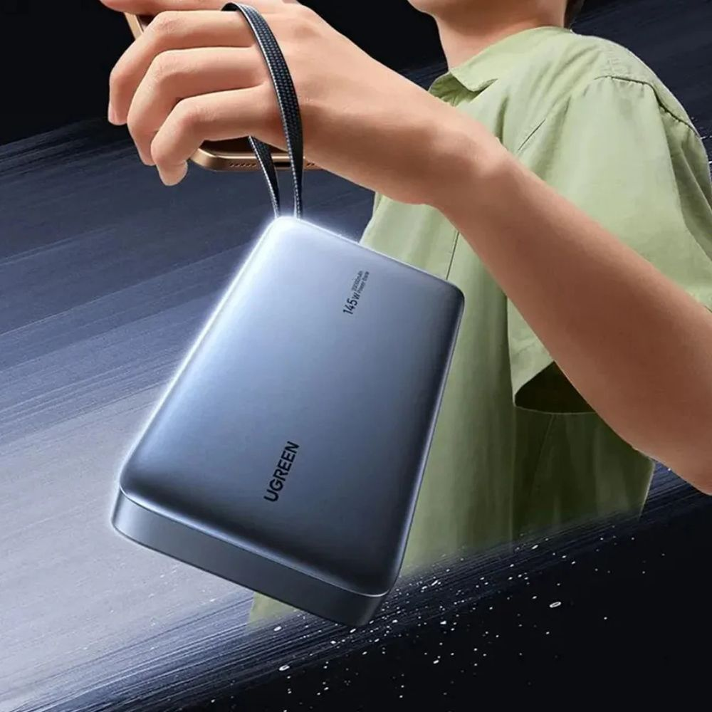 Osoba trzyma szary power bank na pasku.