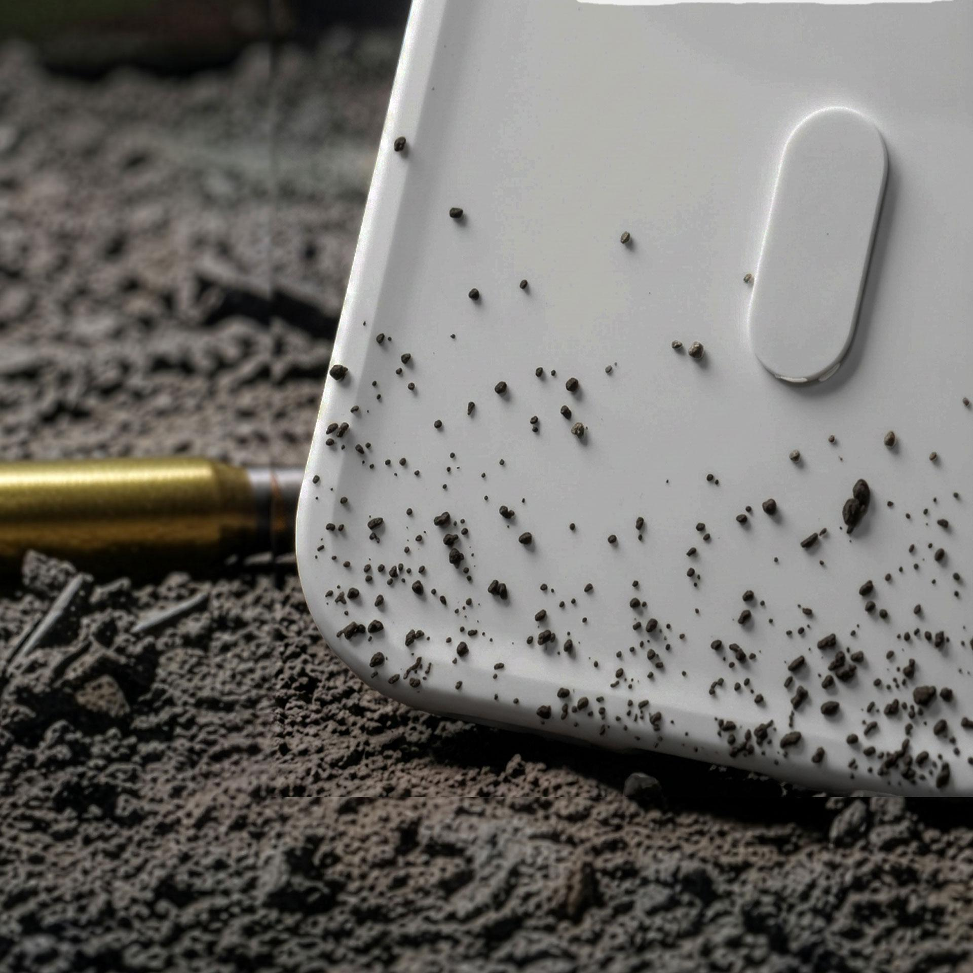 Pocisk leży na szarym gruzie obok białego przedmiotu.