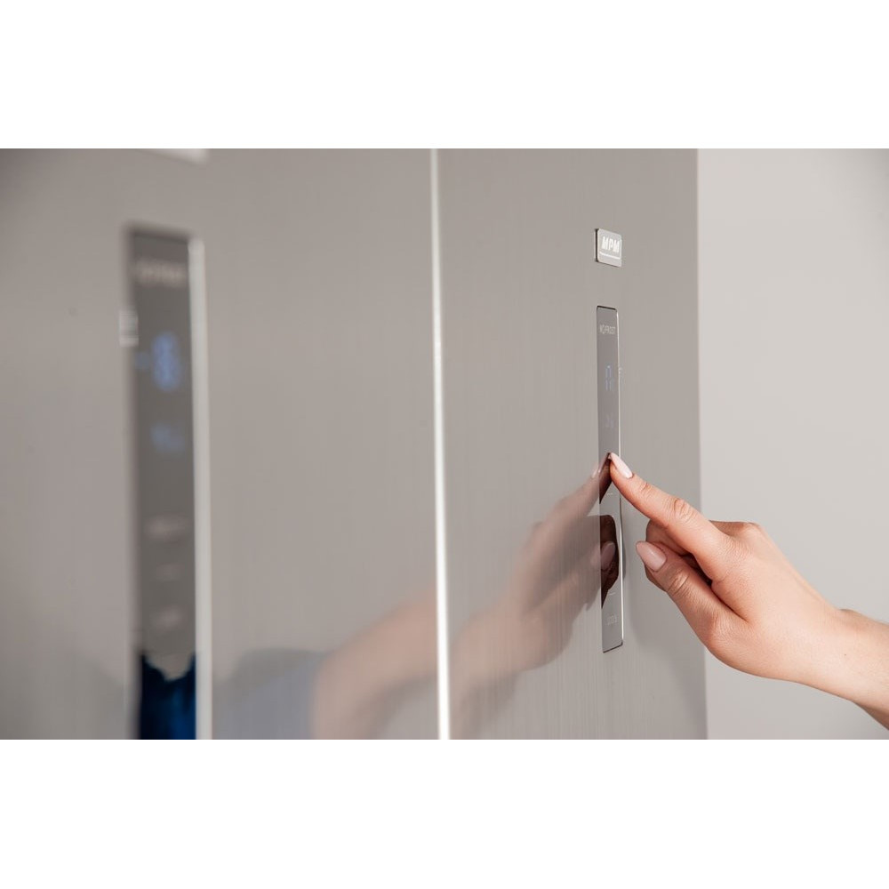 Ręka naciska przycisk na lodówce.