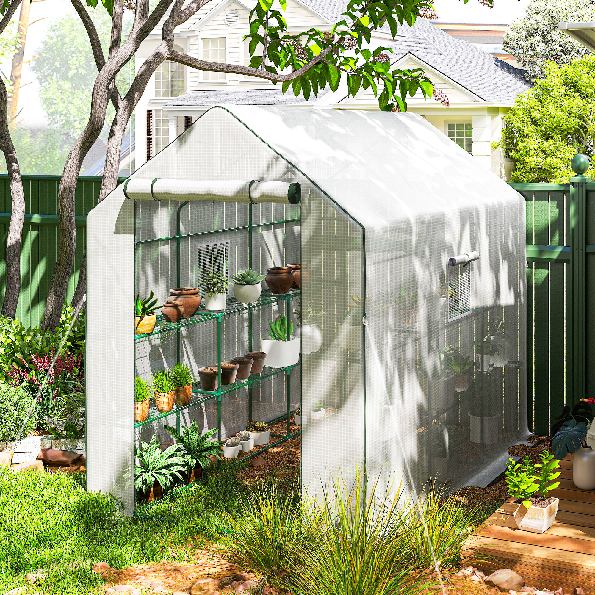 Un invernadero con plantas y macetas en un jardín, una casa al fondo.