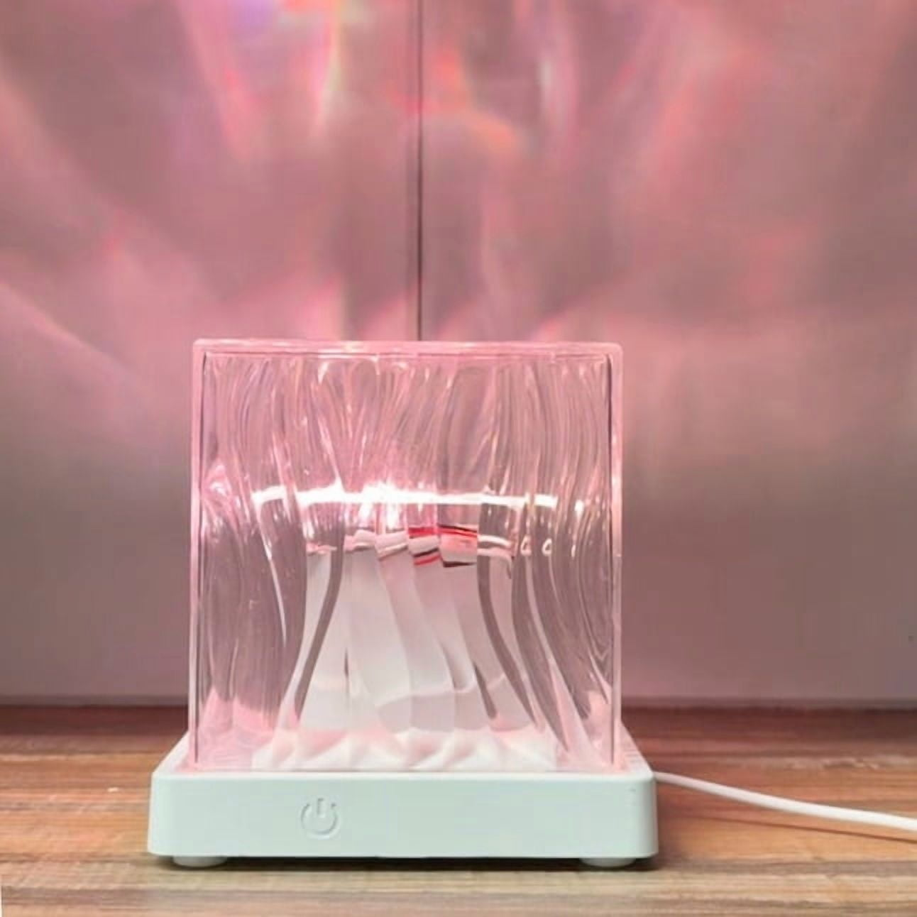 Eine kleine Lampe mit klarem Glasgehäuse wirft rosa Lichtmuster an die Wand.