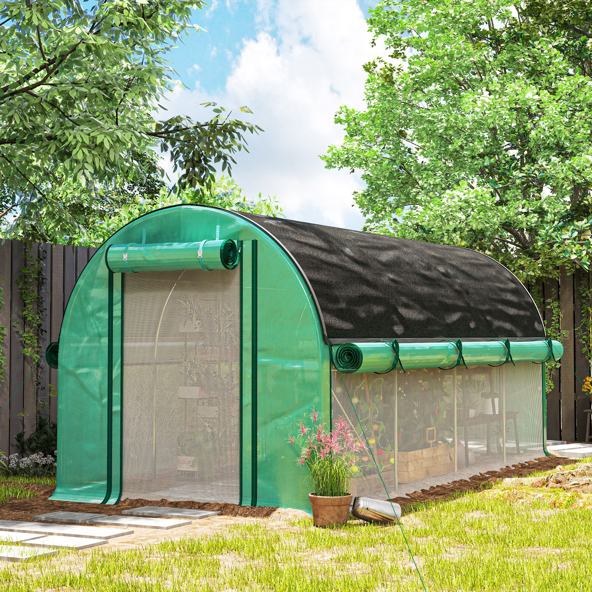 Un invernadero verde con ventanas enrollables está en un jardín bajo árboles.