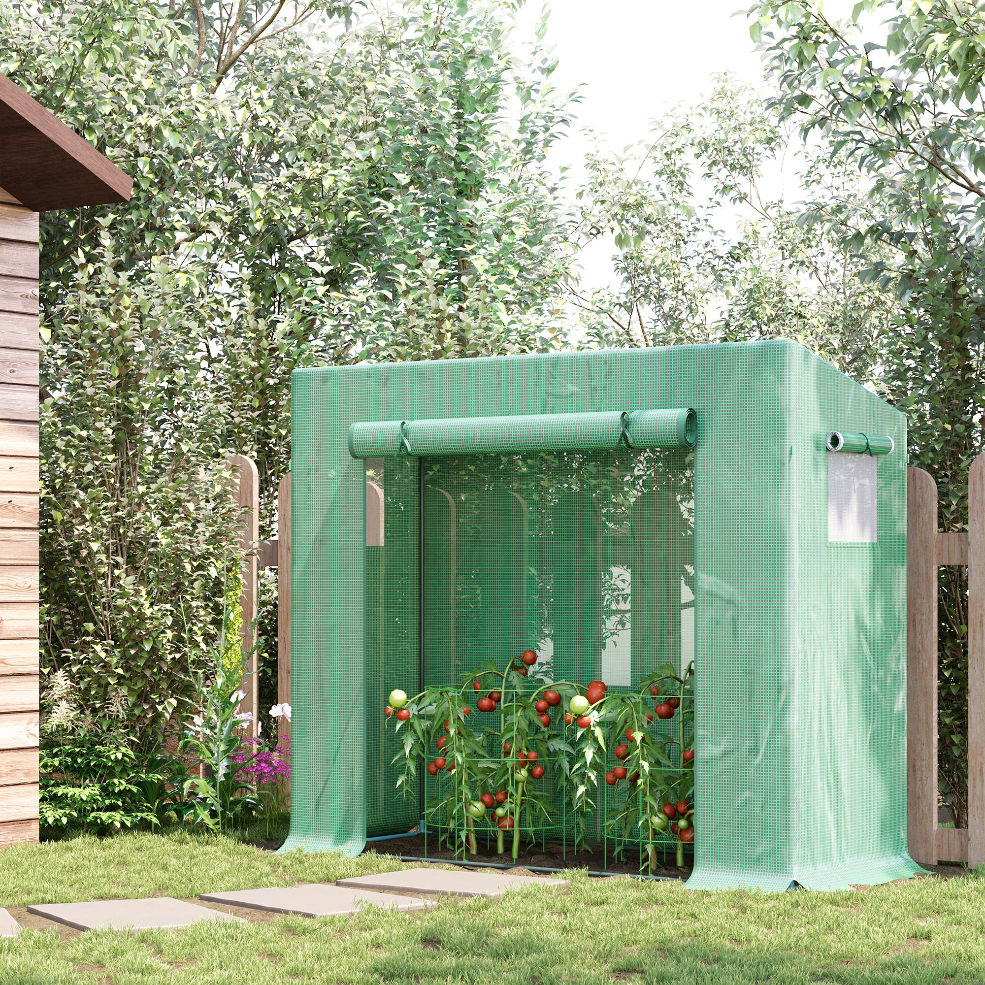Un invernadero verde con plantas de tomate en un jardín junto a un cobertizo de madera.