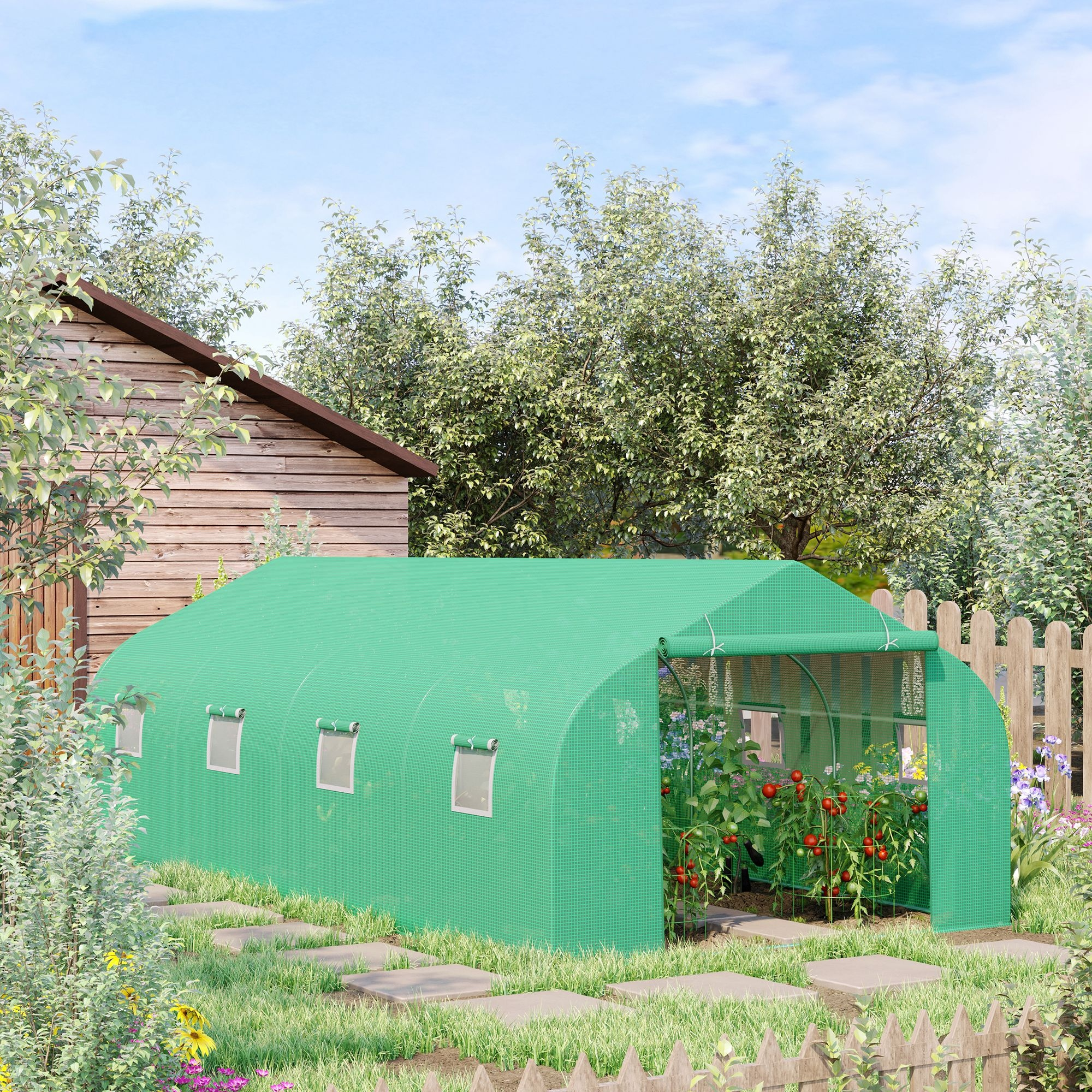 Un invernadero verde con plantas de tomate y un cobertizo de madera en un jardín.