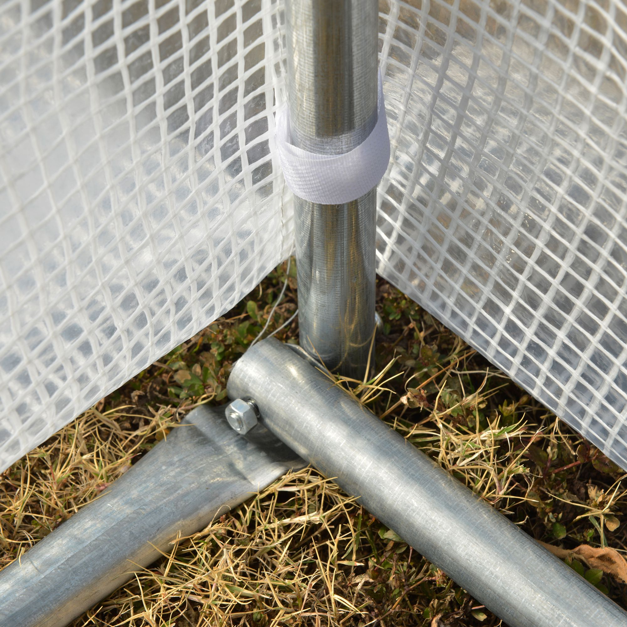 Primer plano de la estructura de invernadero con postes metálicos y lámina de plástico transparente.