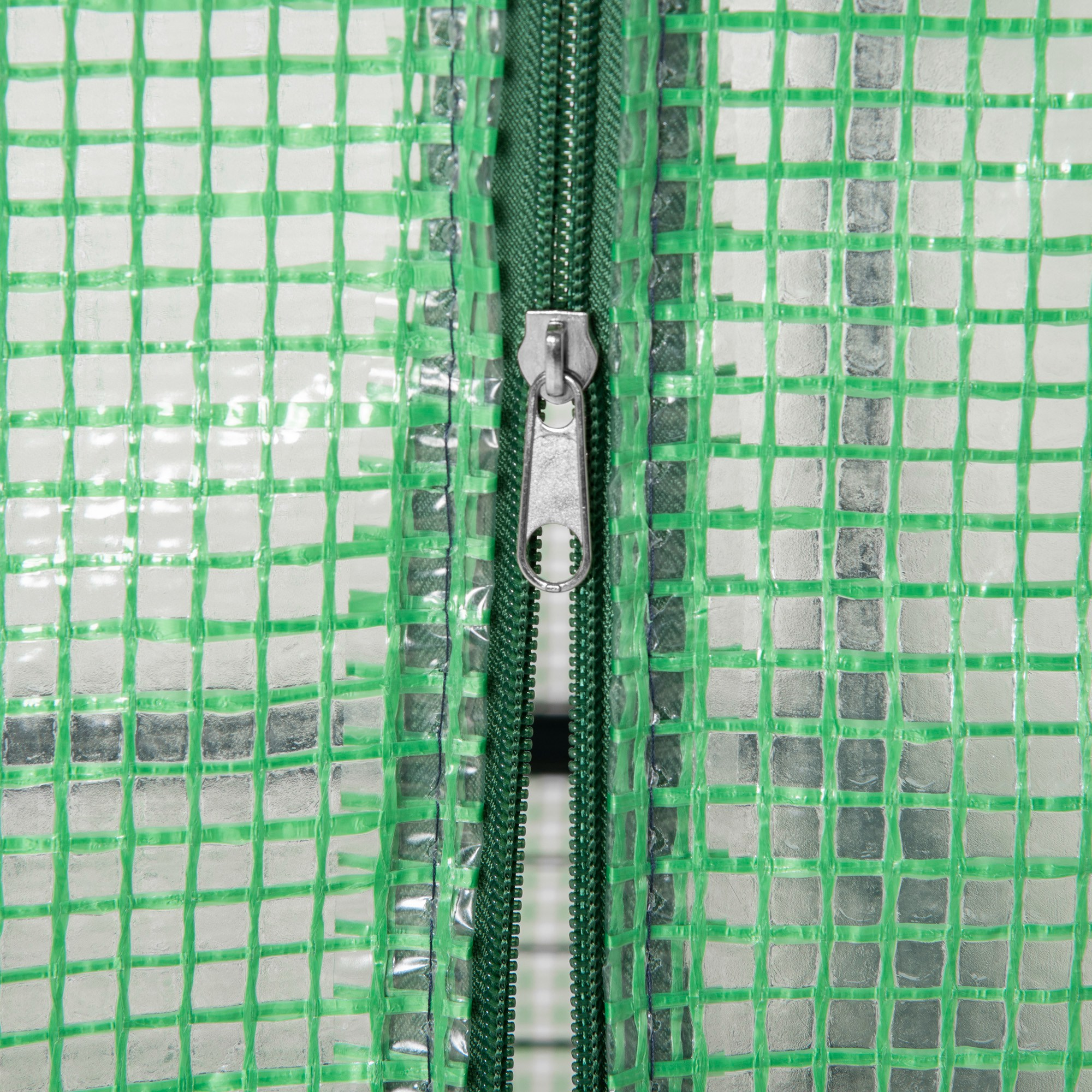Primer plano de una cremallera verde sobre una superficie transparente con patrón de rejilla.