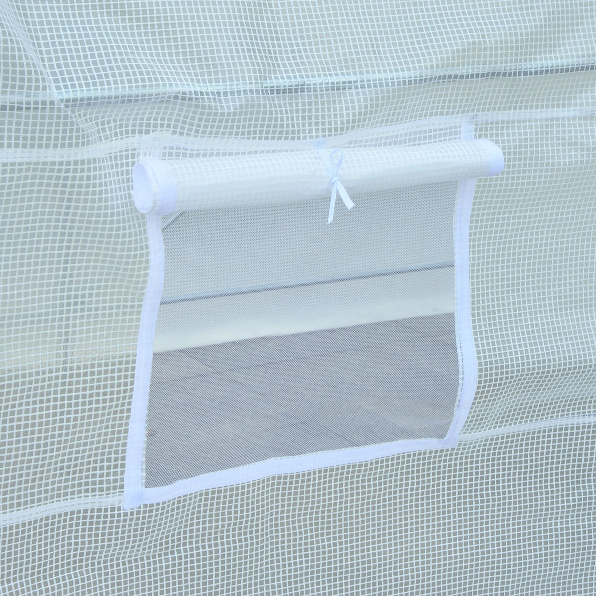 Una ventana de puerta de invernadero blanca con persiana enrollada sujeta con una corbata.
