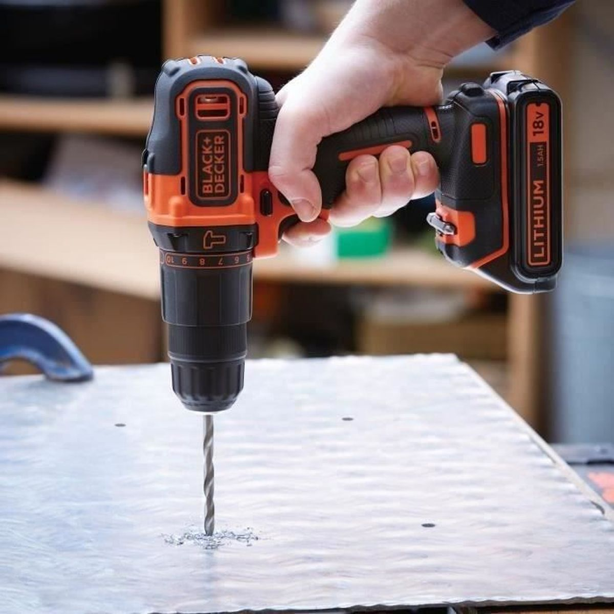 Eine Person bohrt mit einem Akku-Bohrschrauber von Black+Decker ein Loch in ein Metallblech.