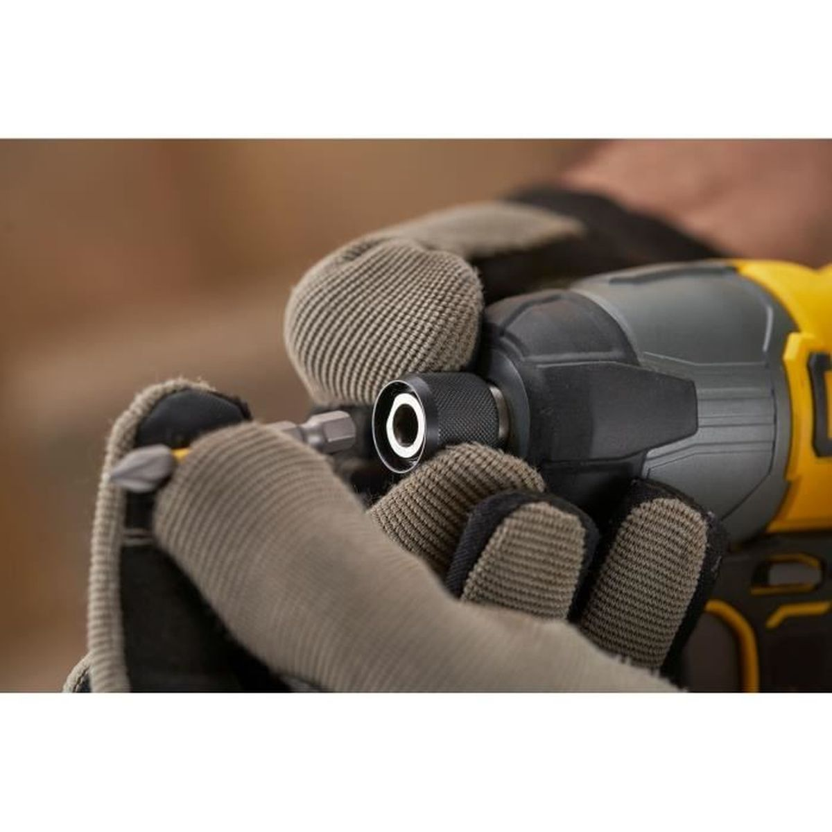 Gummierte Handschuhe halten einen Akkuschrauber mit Bits. Nahaufnahme.