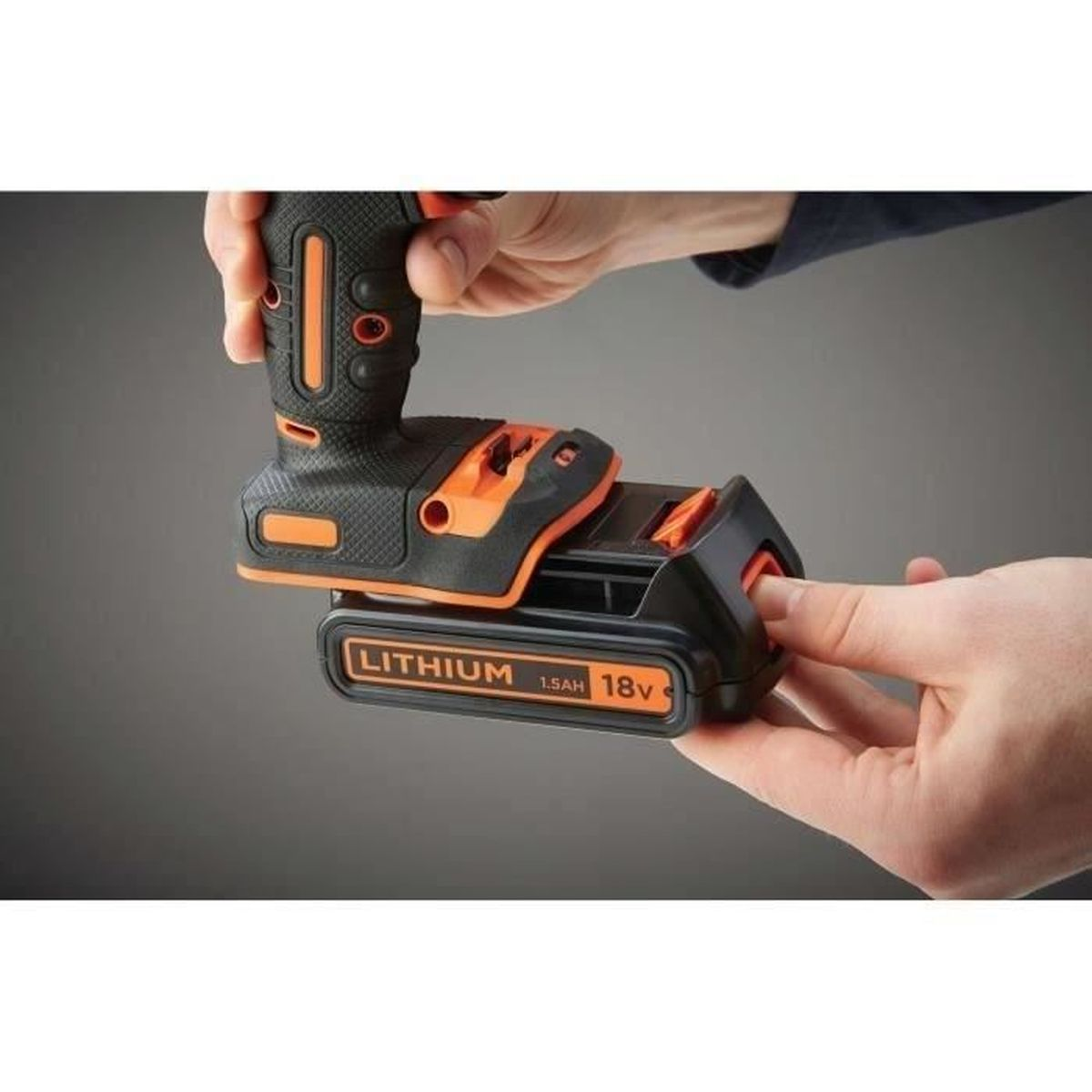Eine Hand setzt einen schwarzen und orangen Akku in ein Elektrowerkzeug ein.