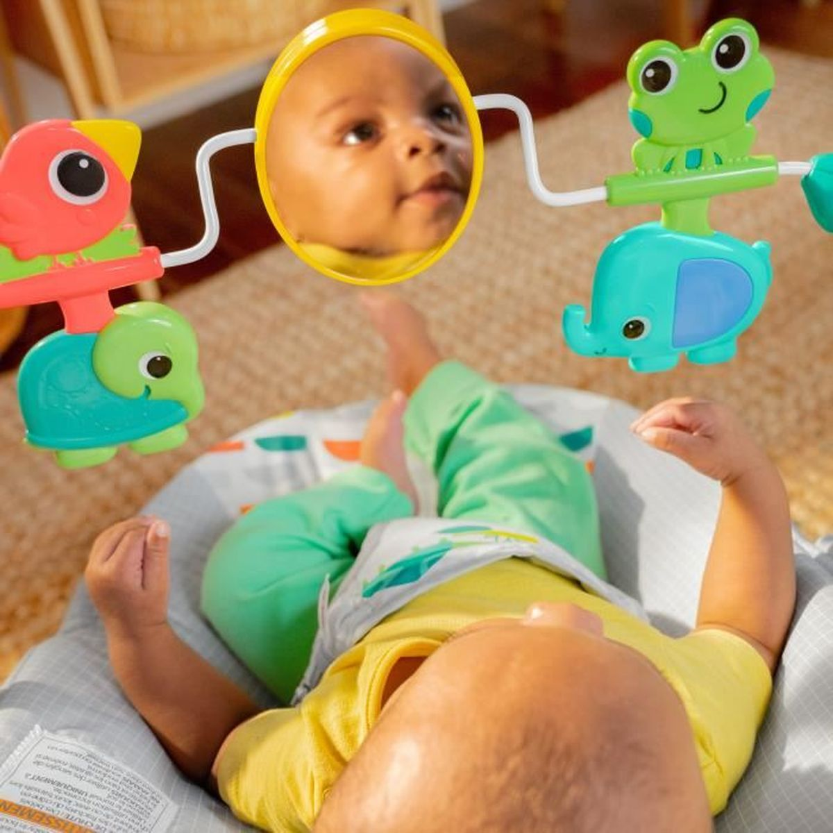 Baby liegt auf dem Rücken; Spielzeug mit Spiegel, Frosch, Elefant und Vogel.