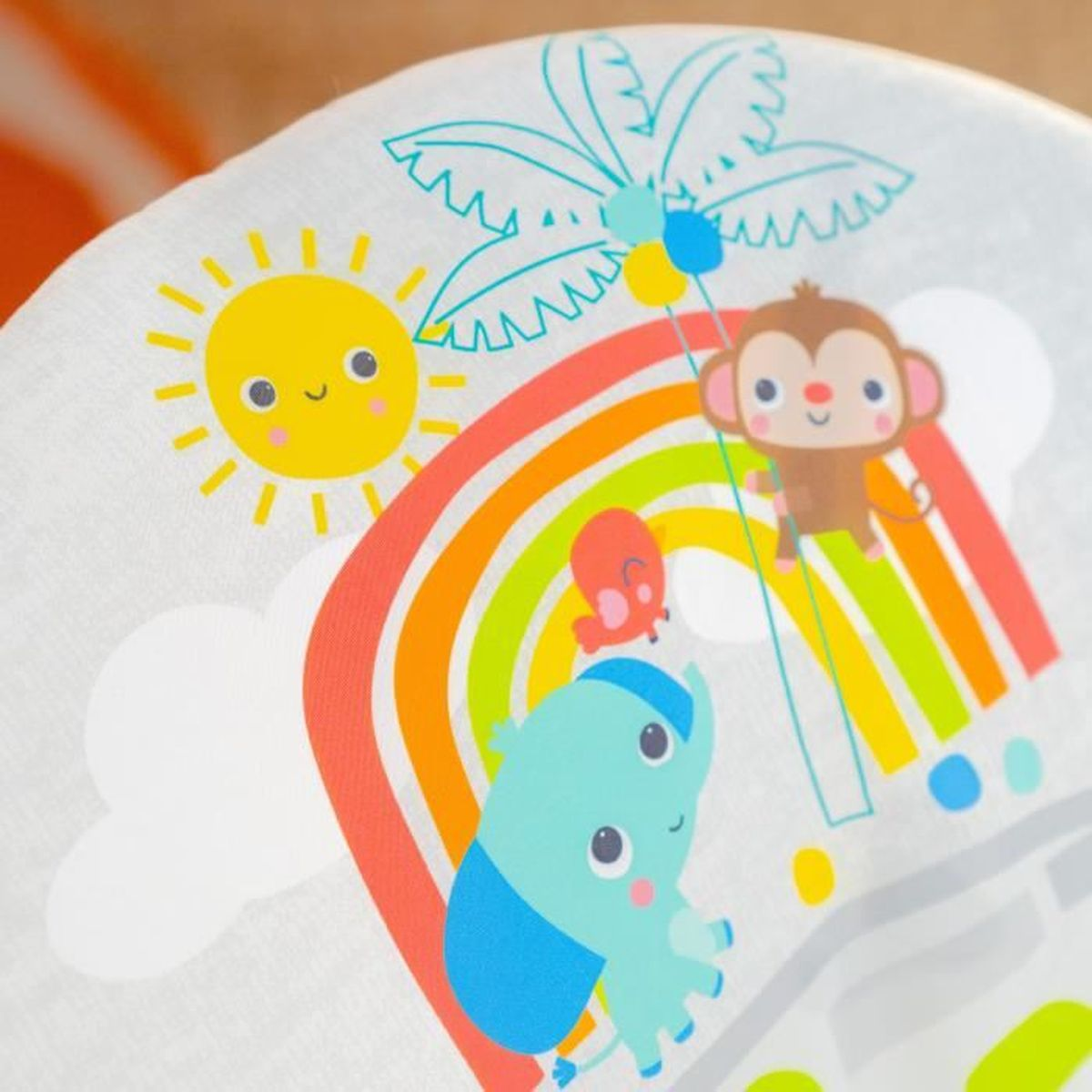 Ein Elefant, Affe, Schmetterling, Sonne, Regenbogen und Palmenblatt auf hellem Stoff.