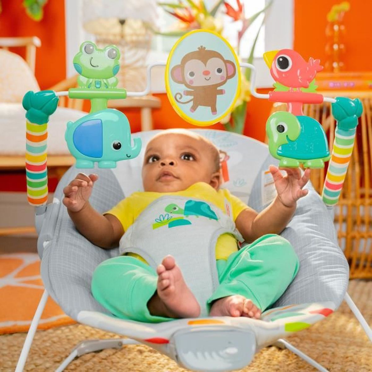 Ein Baby sitzt in einer Babyschaukel mit Spielzeug-Tieren wie Elefant, Frosch und Affe.