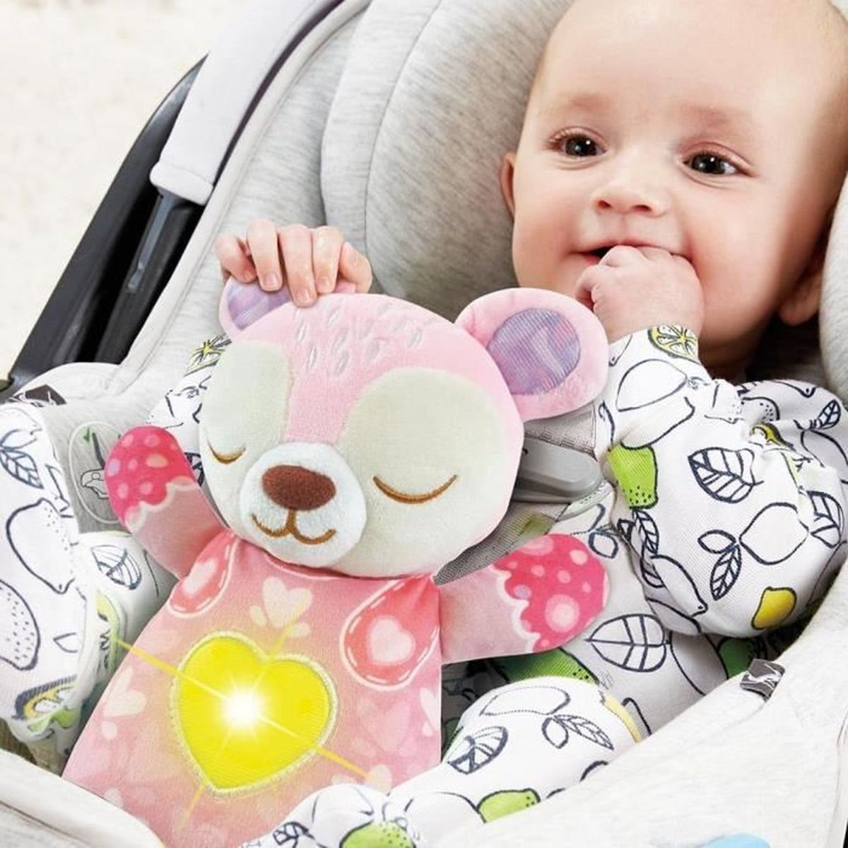 Ein Baby hält ein rosa Teddybär-Spielzeug mit einem leuchtenden Herz.