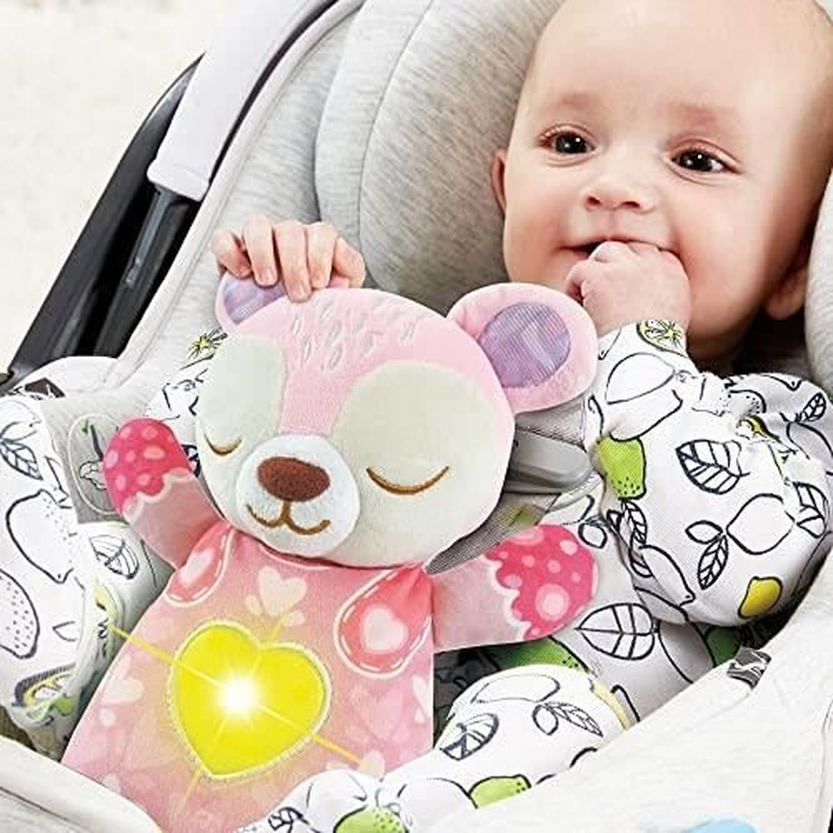 Ein Baby hält einen rosa Teddybären in einem Autositz mit leuchtendem Herzen.