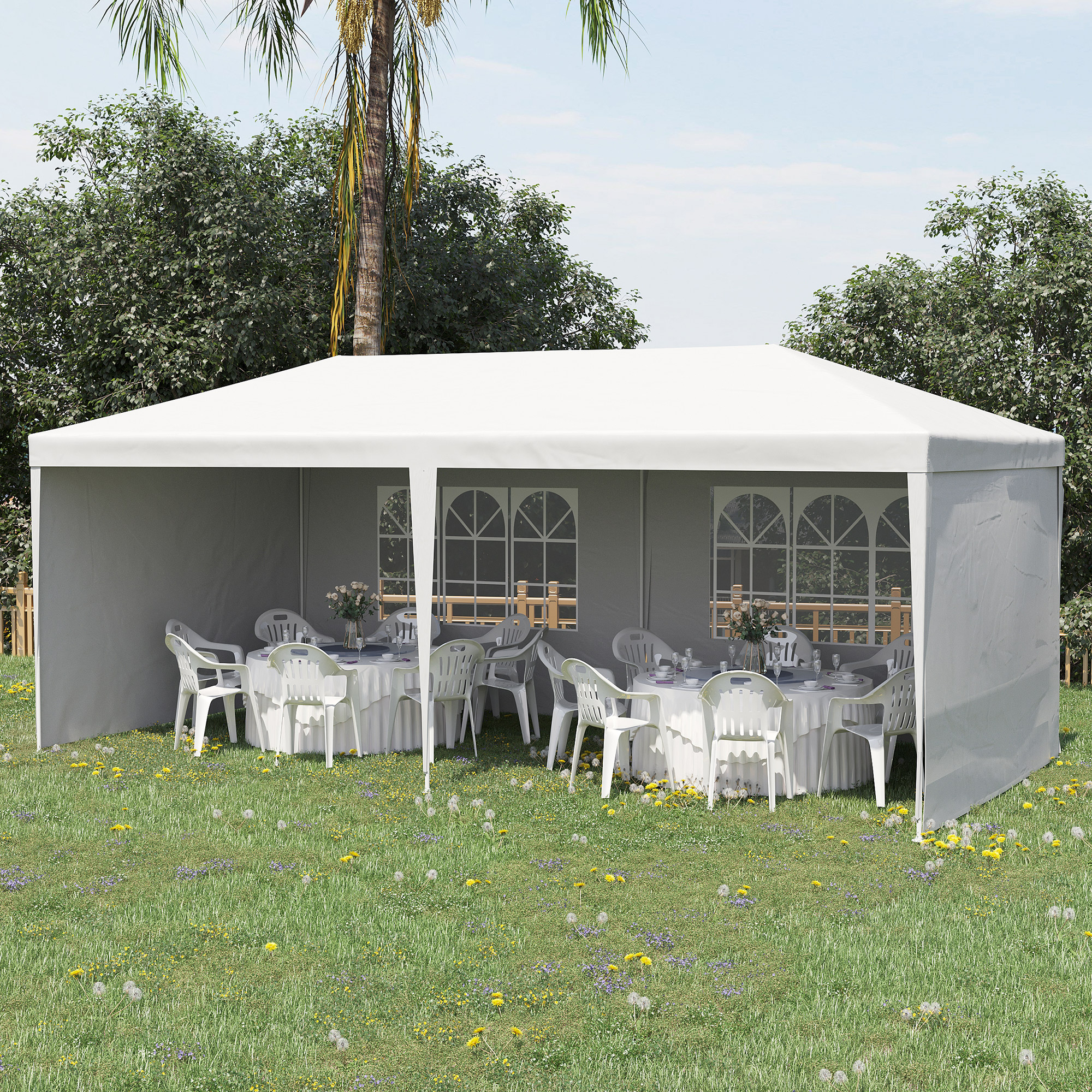 Una tenda bianca è allestita sull'erba con tavoli e sedie, pronta per un evento.