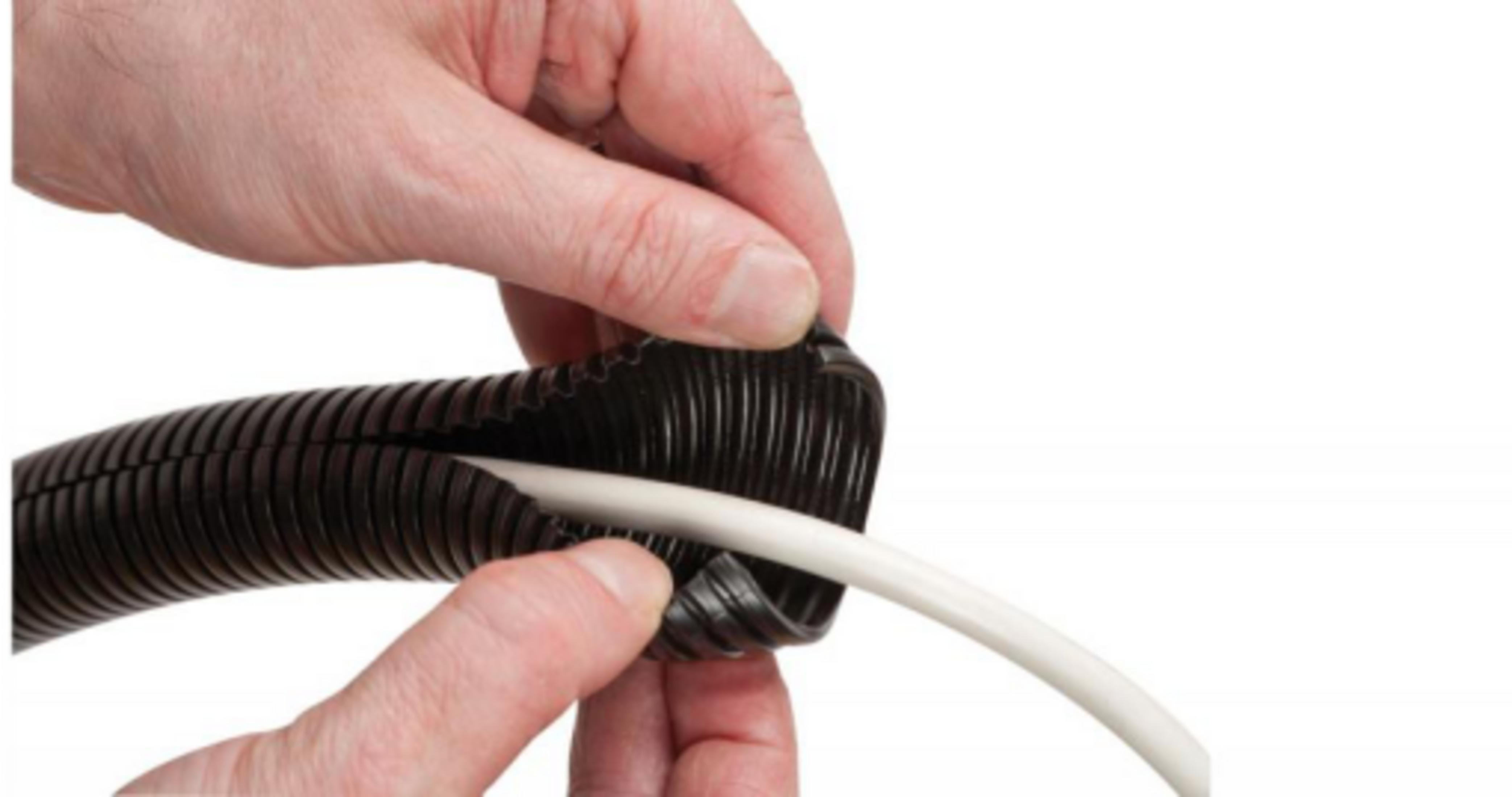 Mani che inseriscono un cavo bianco in un tubo corrugato nero.