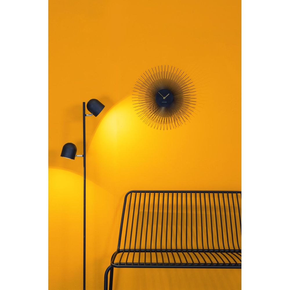 Un banc noir et une horloge murale sont accrochés à un mur jaune.