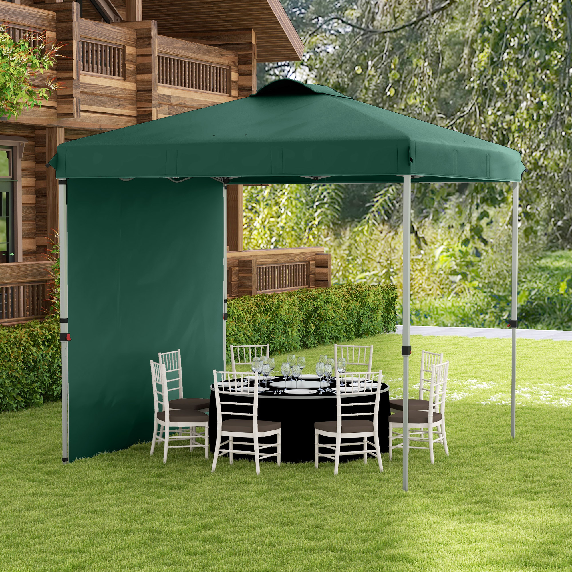 Una carpa verde con mesa puesta y sillas en un jardín frente a una casa de madera.