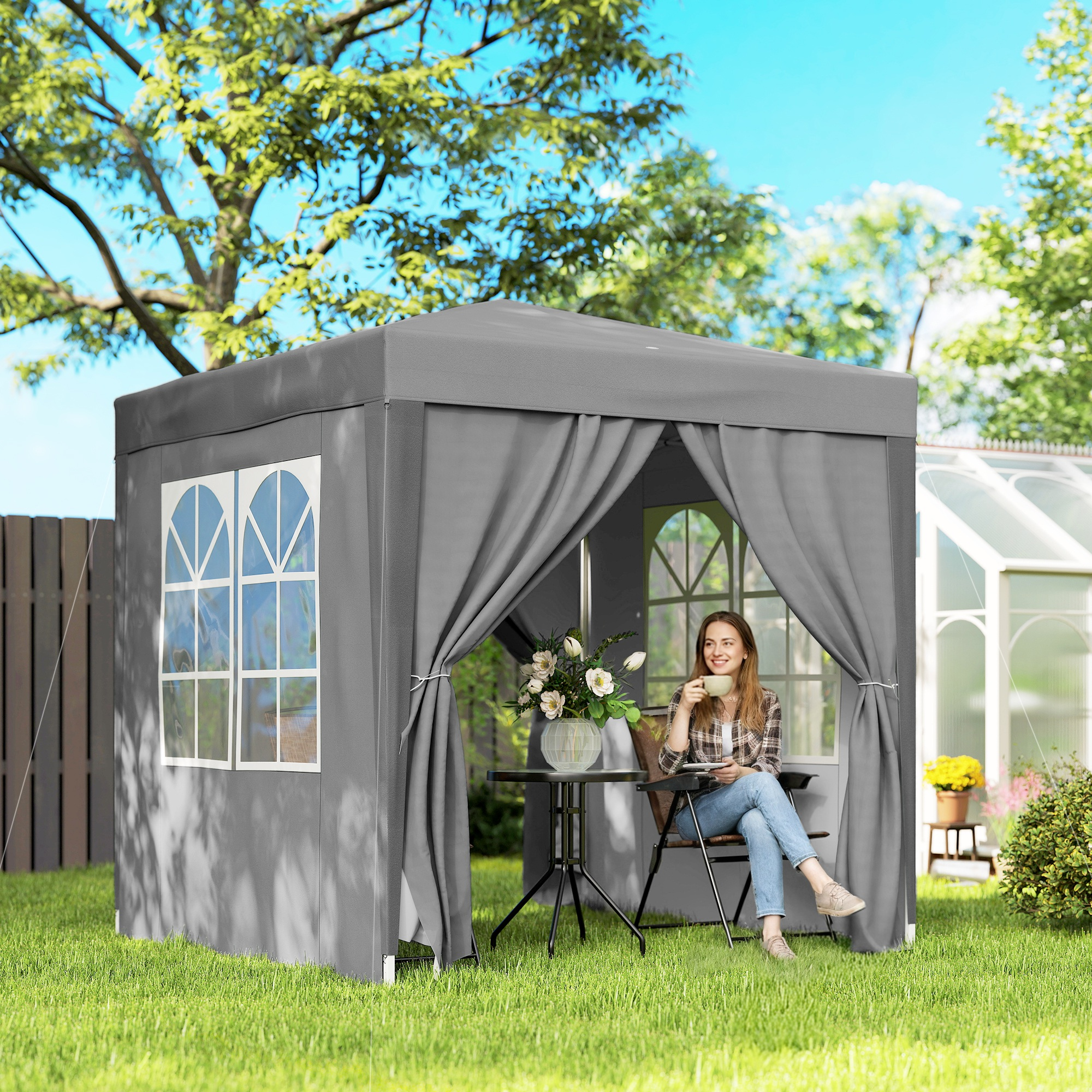 Donna beve caffè in un gazebo da giardino grigio con serra.