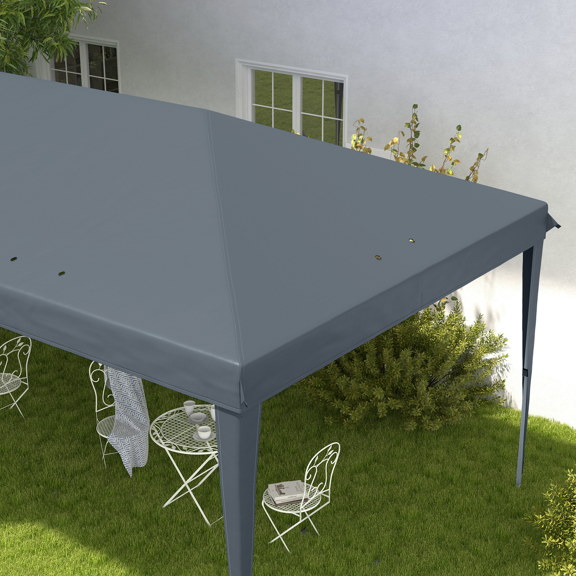Un gazebo grigio copre mobili da giardino bianchi su un prato vicino a una casa.