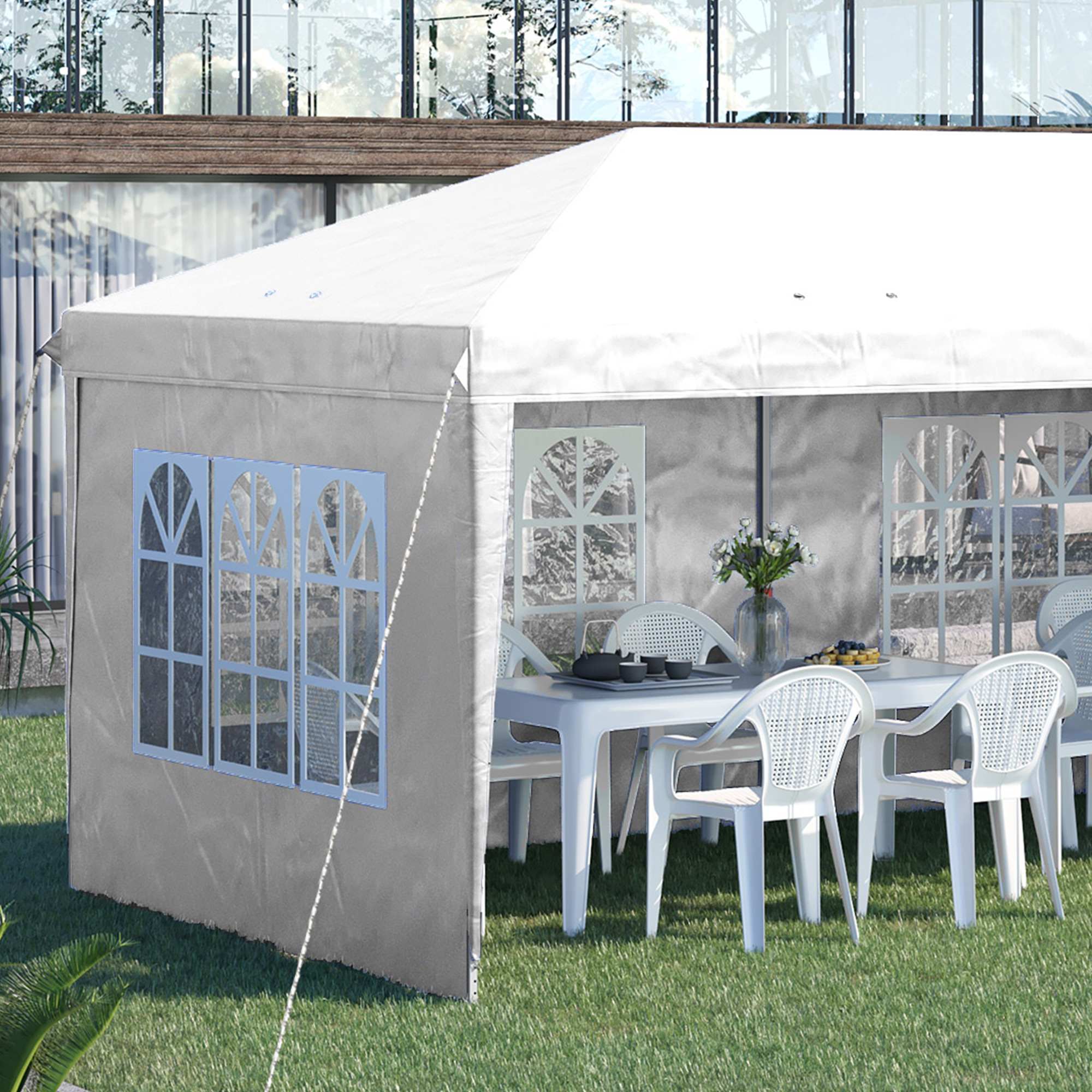 Tenda bianca da festa con tavolo e sedie sull'erba.