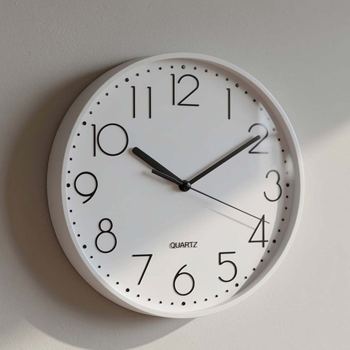 Weiße Wanduhr mit schwarzen Ziffern und Zeigern, die 10:09 Uhr anzeigt.