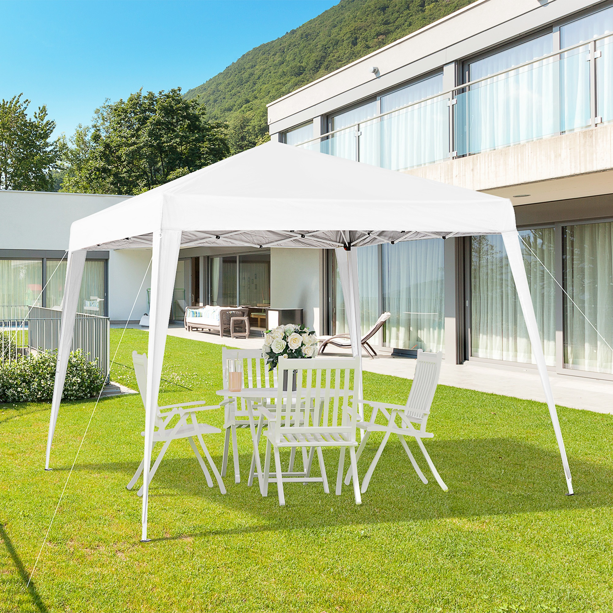 Gazebo bianco con tavolo e sedie su prato verde davanti a casa moderna.