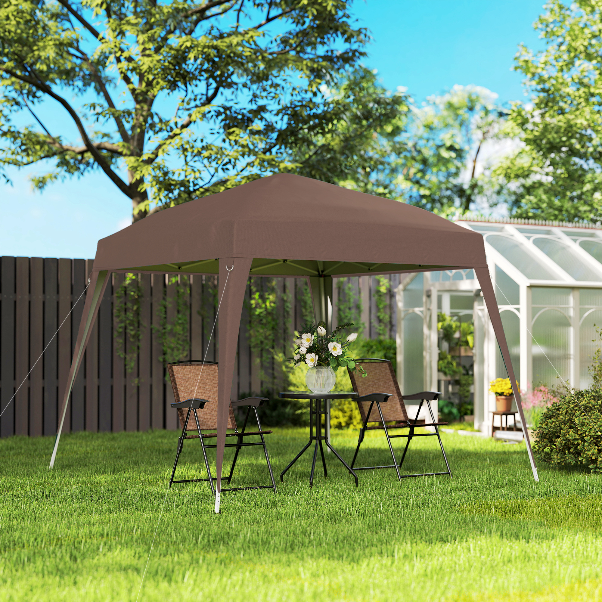 Una tenda a baldacchino marrone siede sull'erba verde con tavolo e sedie.