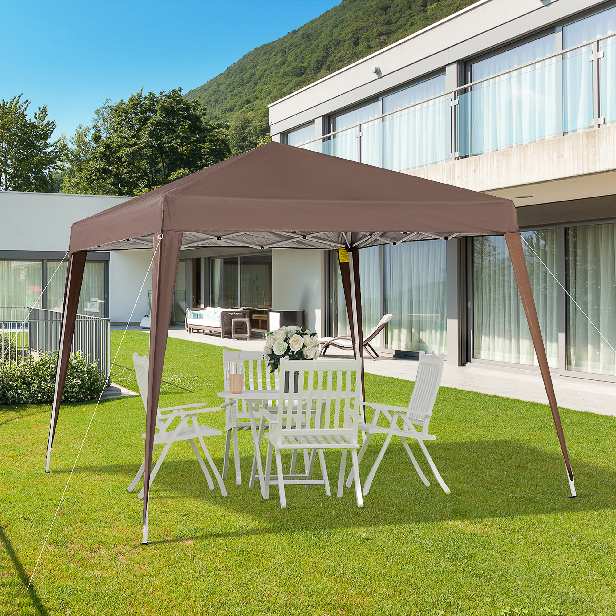 Una carpa marrón está montada en un césped verde con muebles de patio blancos.
