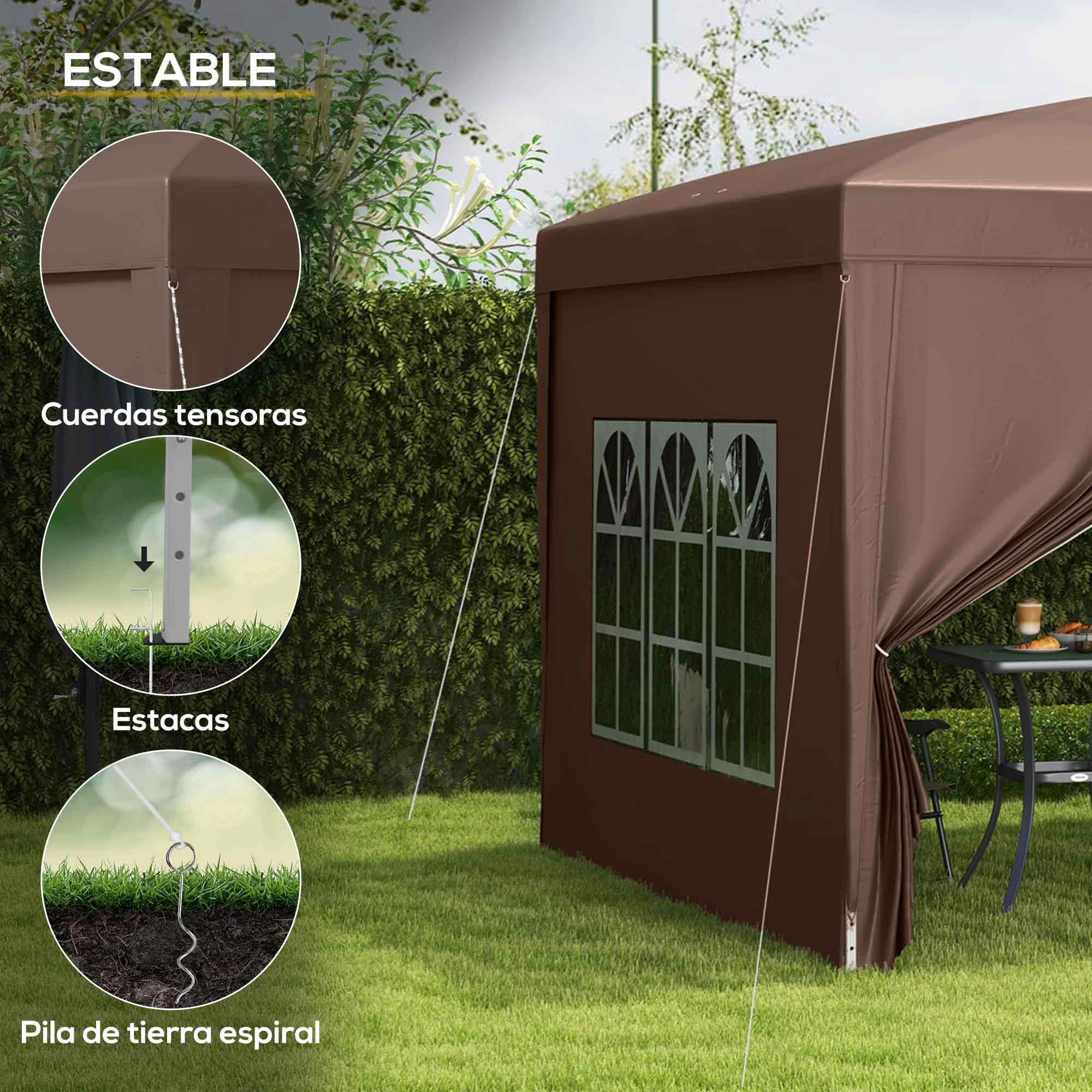 Una carpa marrón con ventanas se alza sobre césped junto a un seto y una mesa.