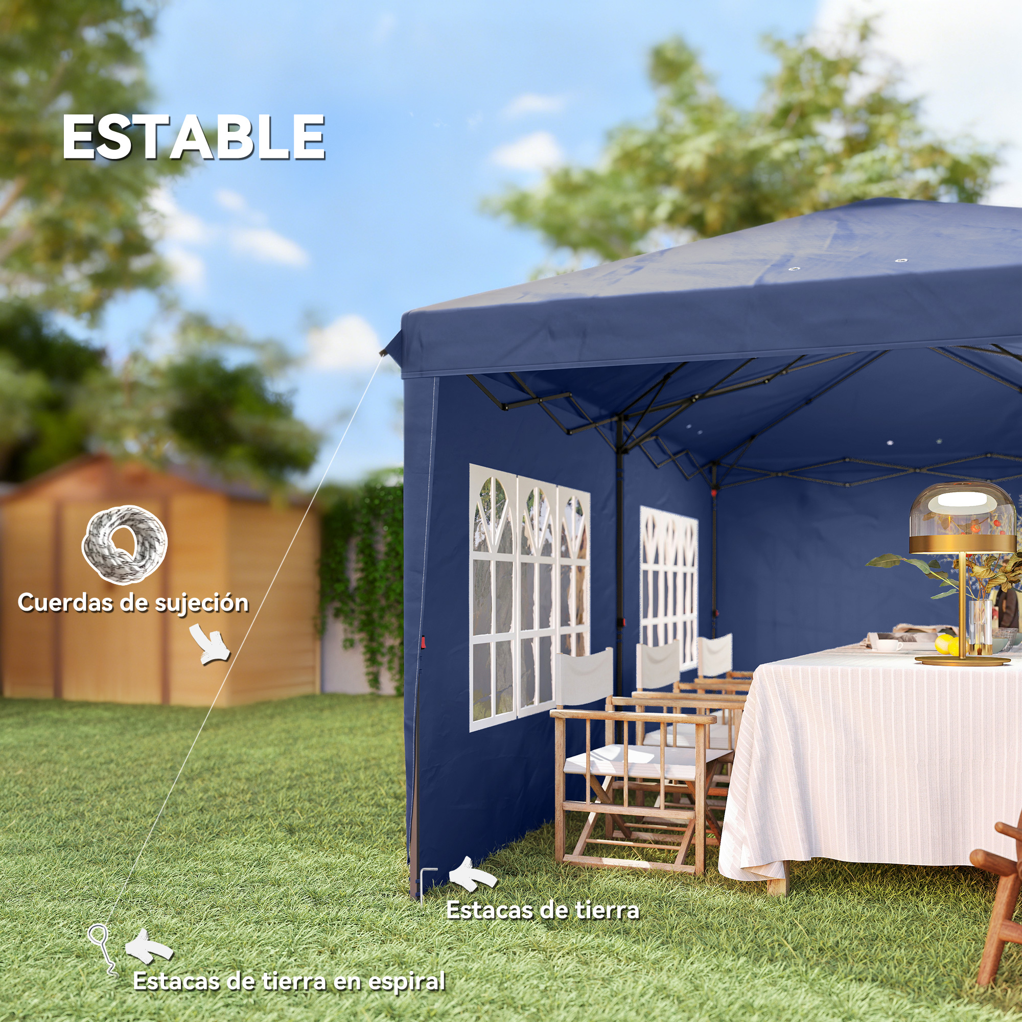 Una carpa azul marino con ventanas se alza sobre césped, con una mesa y sillas cerca.