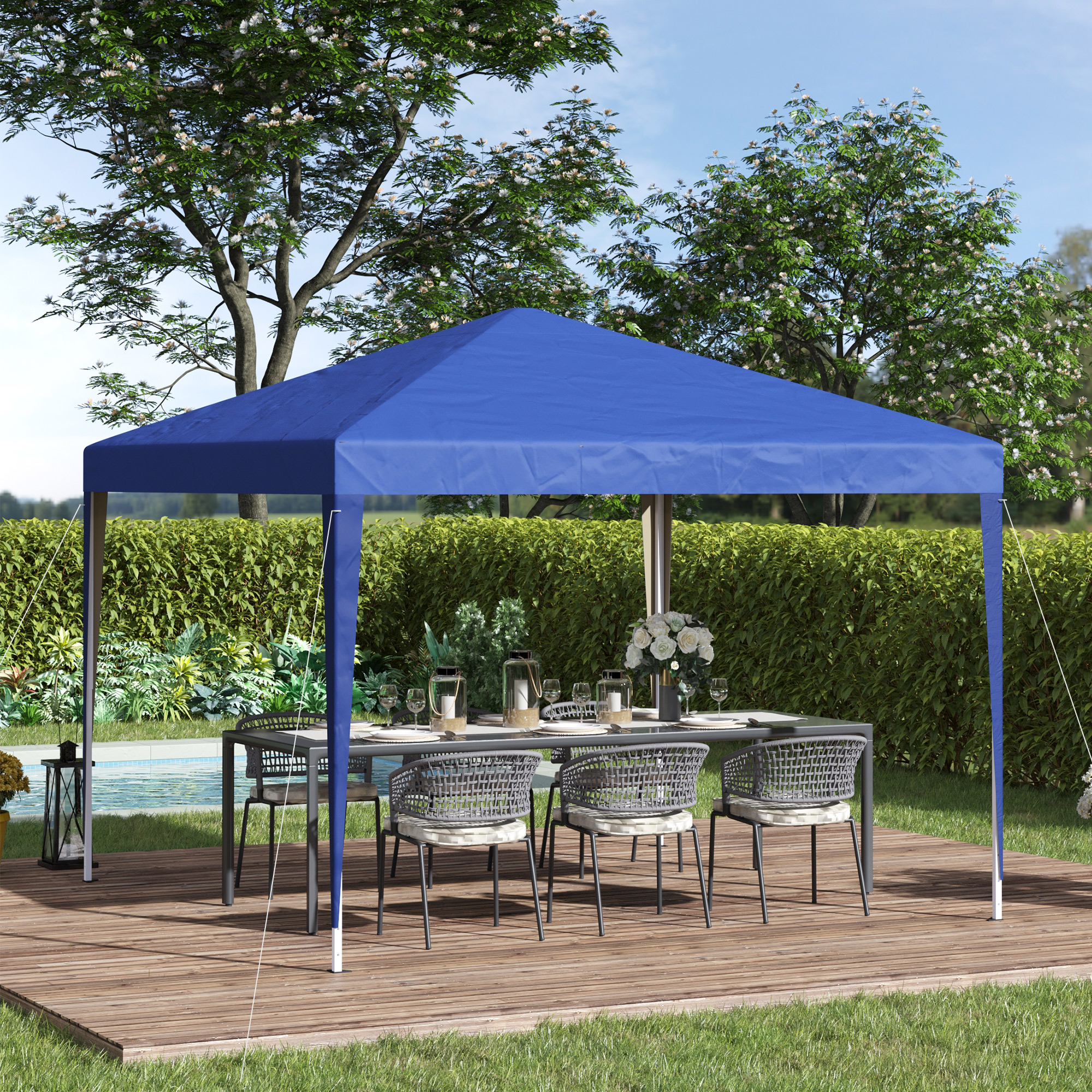 Una tettoia blu copre un tavolo da pranzo con sedie su una terrazza di legno in un giardino.