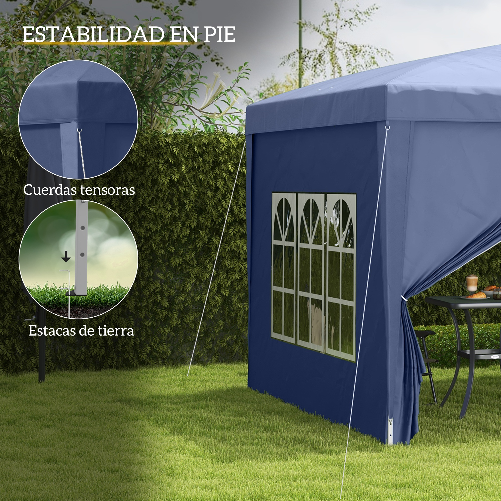Una carpa azul con ventanas sobre césped, junto a un seto. Cuerdas la aseguran.