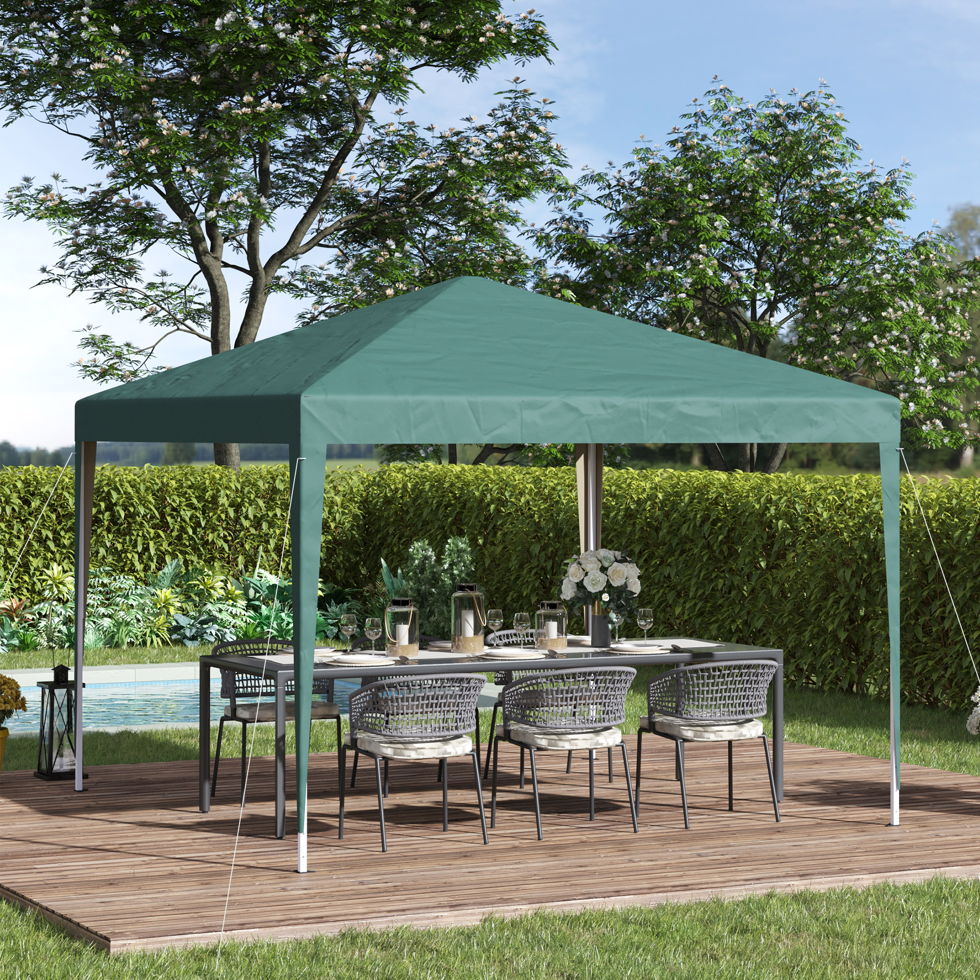 Una carpa verde con mesa y sillas se encuentra en una terraza de madera junto a una piscina.