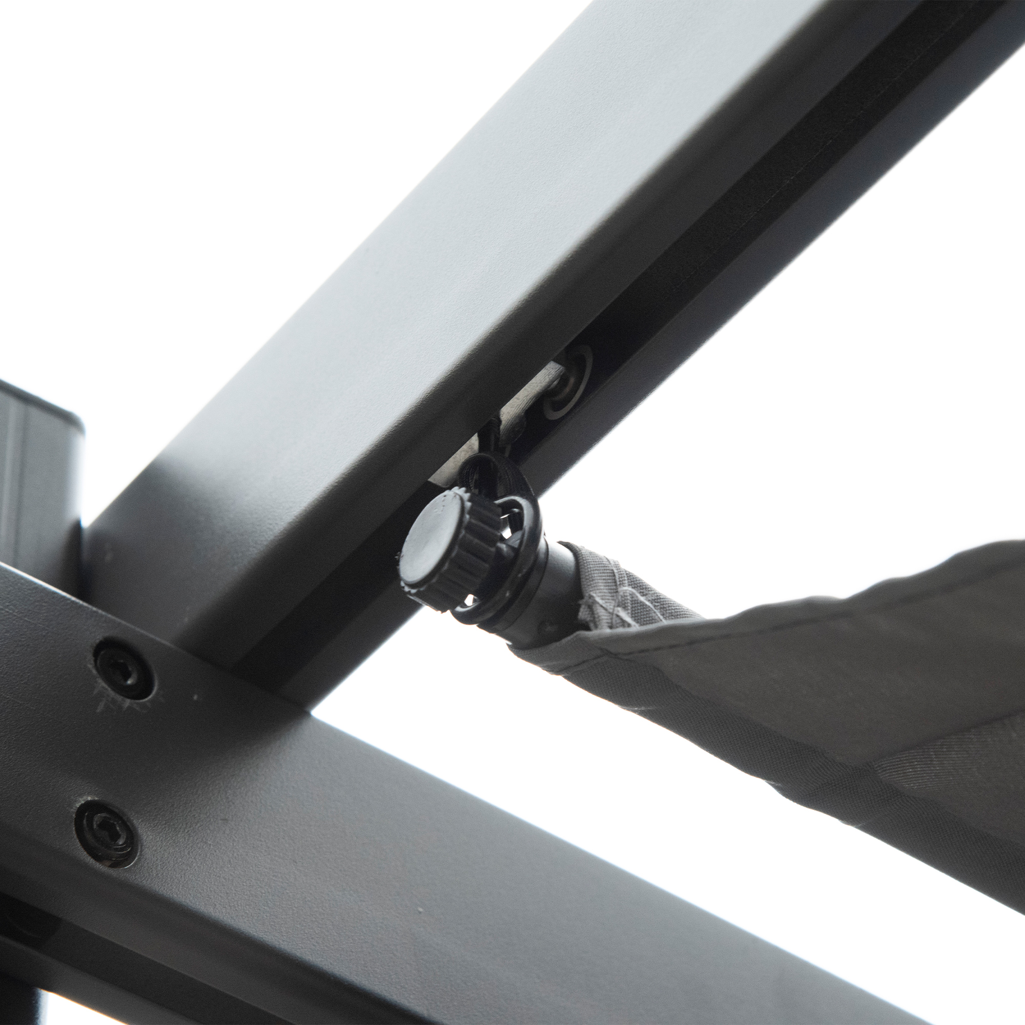Primer plano de una estructura de pérgola oscura con un pomo giratorio negro y toldo de tela.