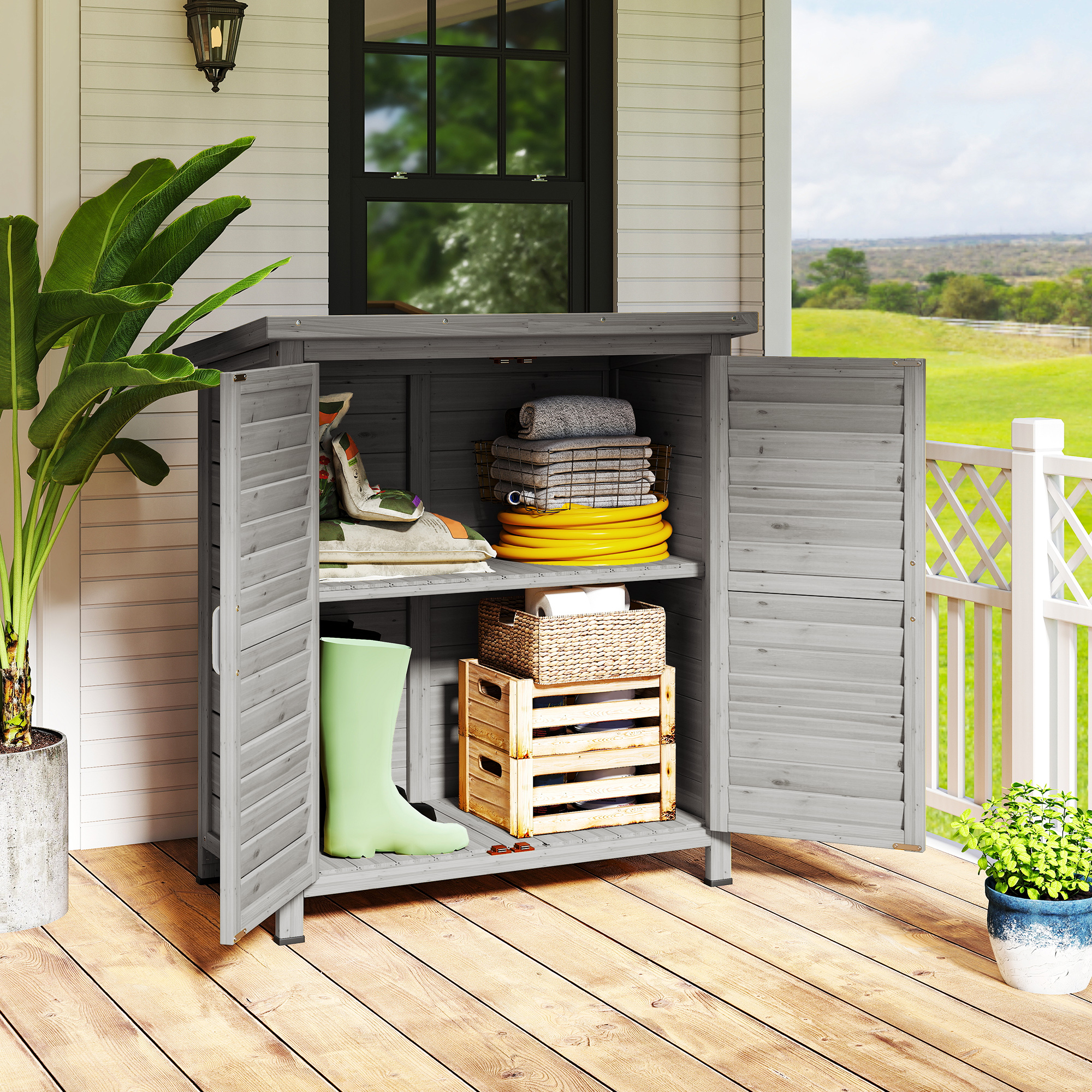 Un armario de exterior gris con puertas abiertas, con herramientas de jardín y toallas.