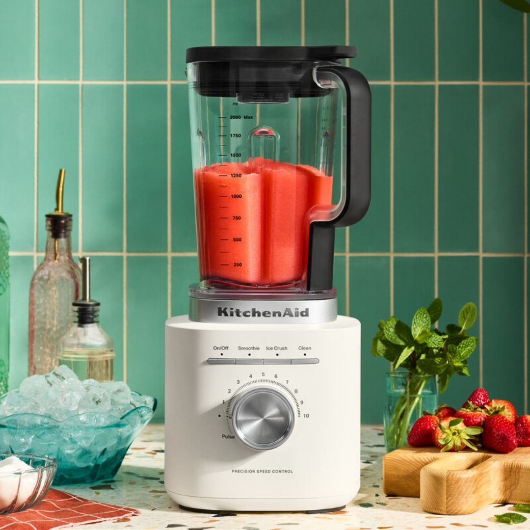 Kırmızı meyve püreli beyaz blender, buz, çilek ve nane yanında.