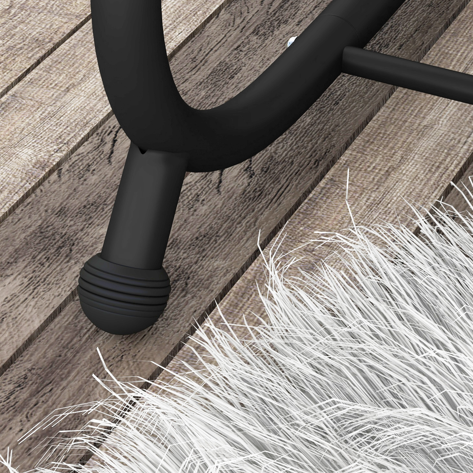Una gamba di sedia nera poggia su assi di legno accanto a un tappeto bianco e soffice.