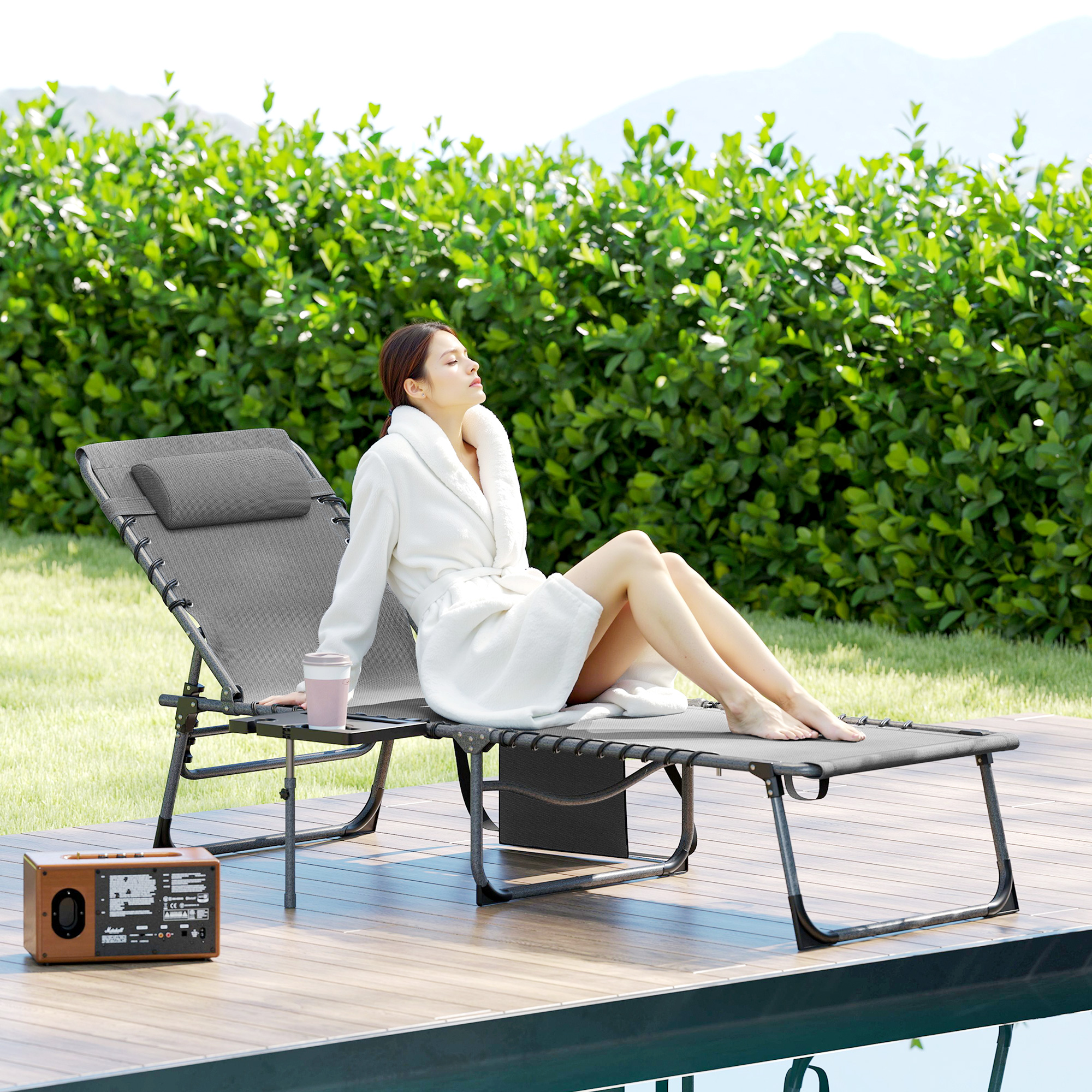 Donna in vestaglia bianca si rilassa su sdraio vicino piscina su deck in legno.