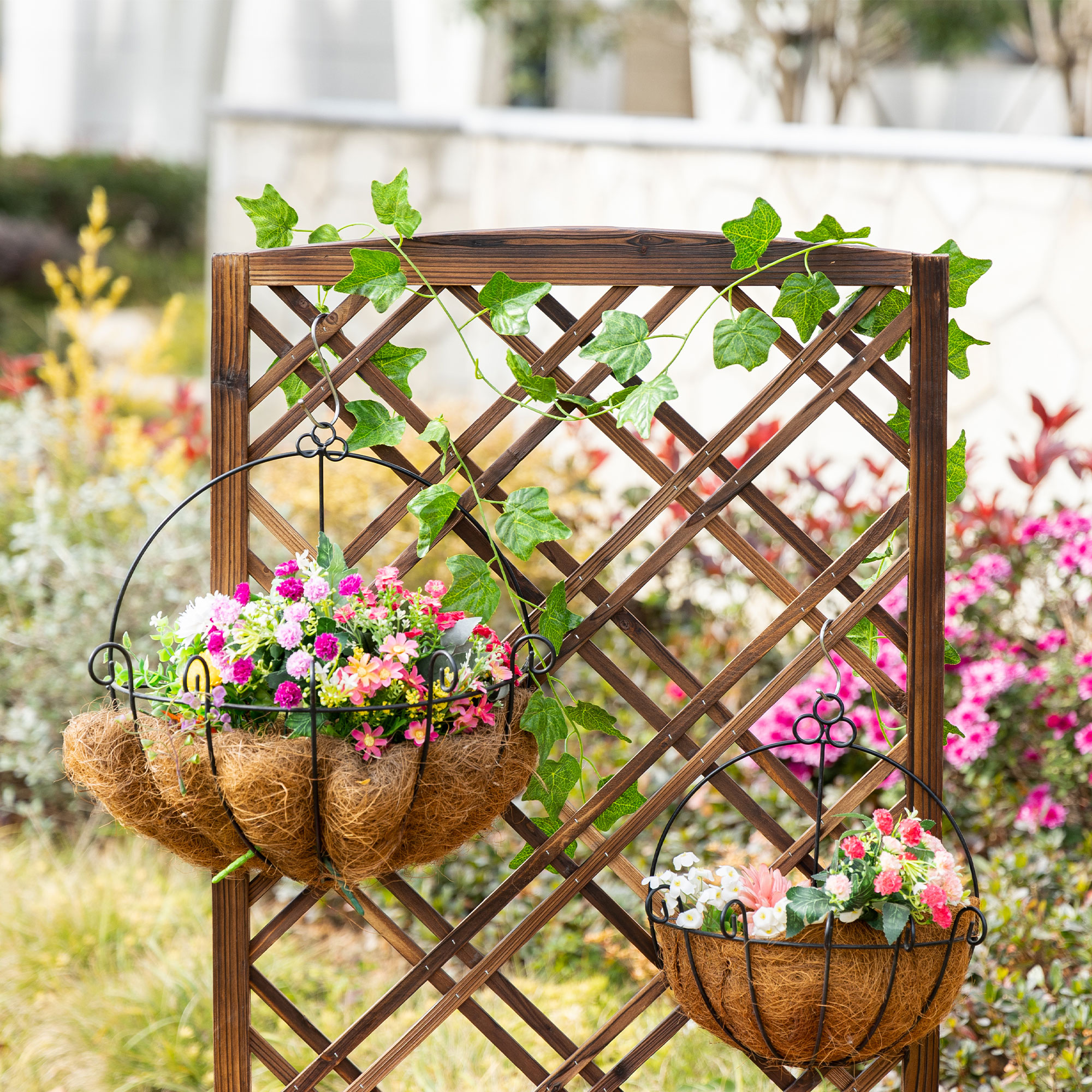 Enrejado de madera con dos cestas colgantes de fibra de coco llenas de flores.