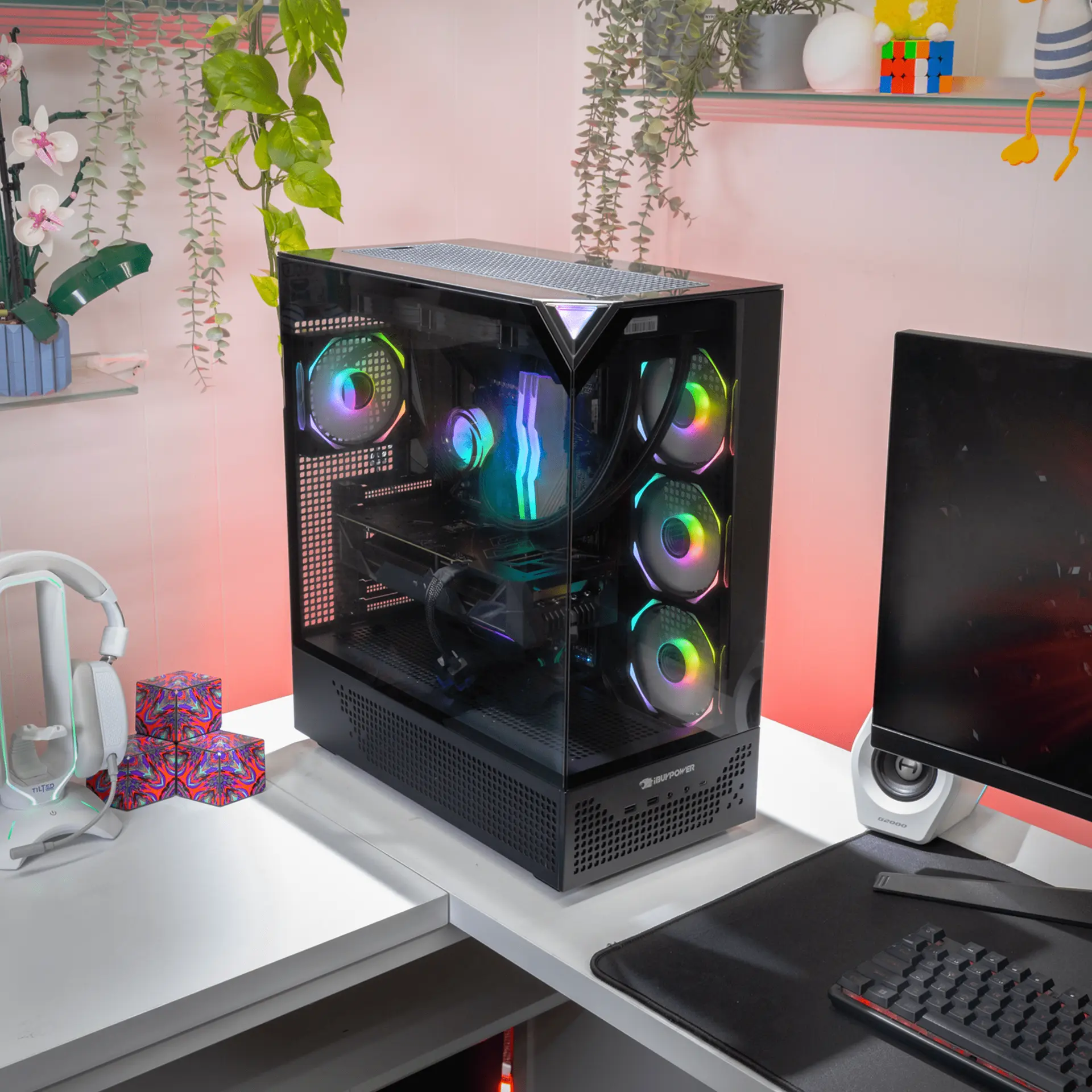 Una caja de PC negra con ventiladores RGB está sobre un escritorio junto a un monitor.