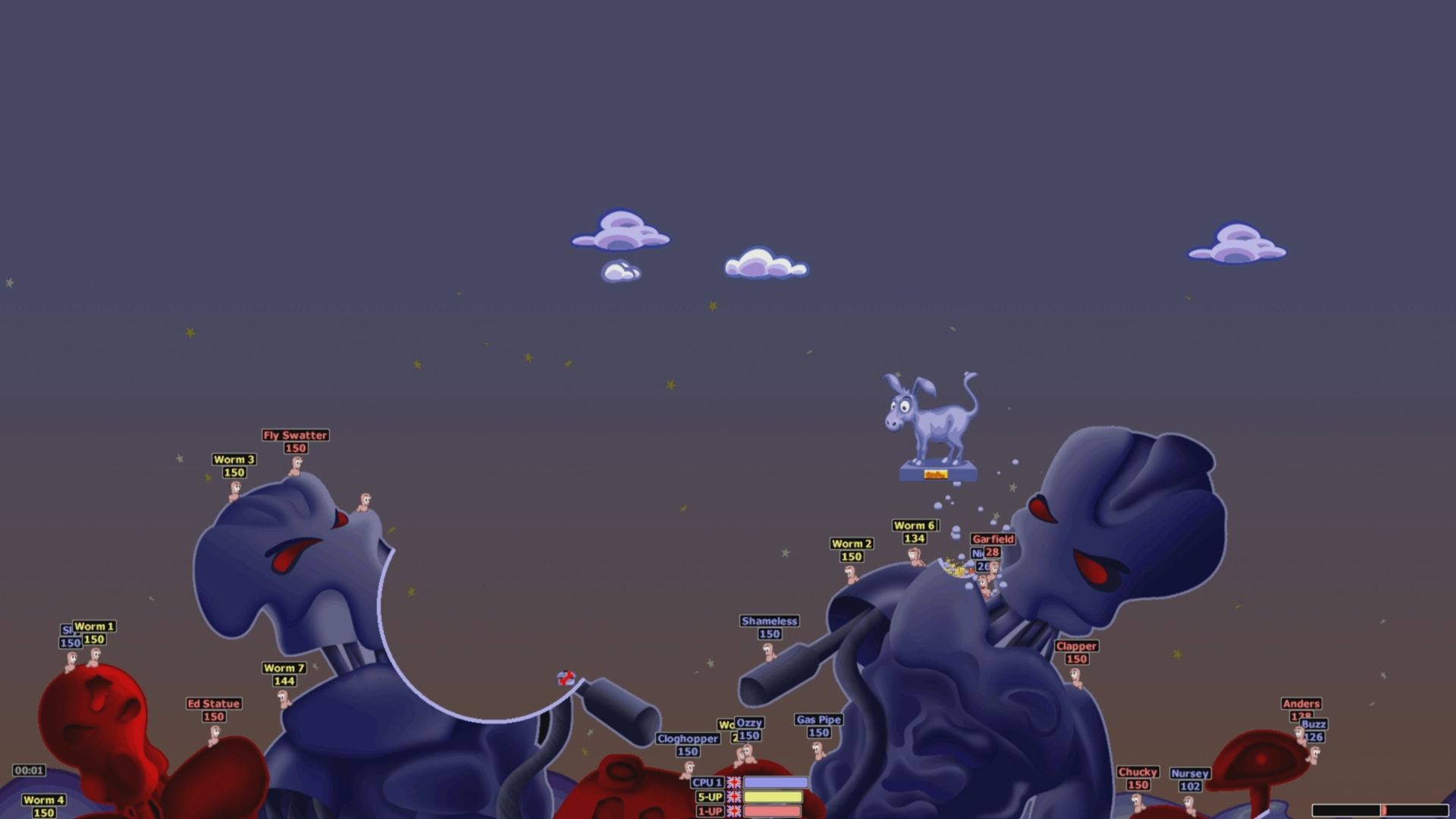 Pokazuje scenę z gry wideo z kreskówkowymi robakami i strukturami.