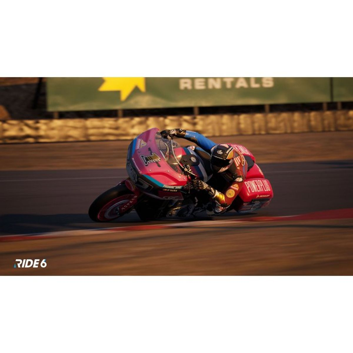 Kierowca na różowym motocyklu pochyla się w zakręcie na torze wyścigowym.