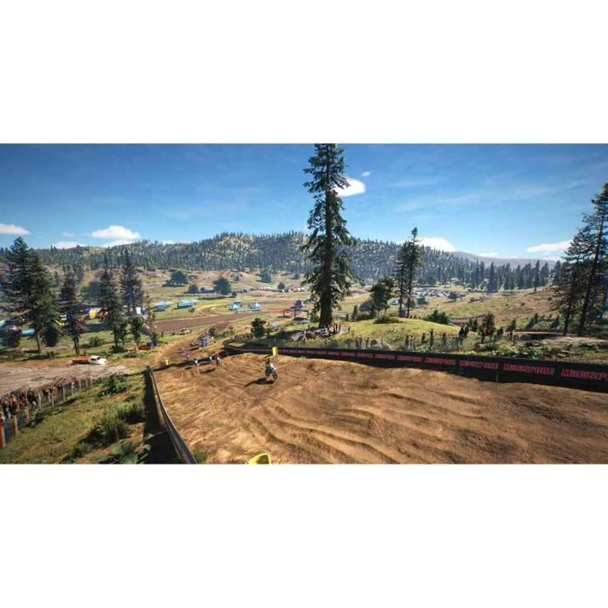 Pista di motocross con corridori su moto in un paesaggio collinare e boscoso.